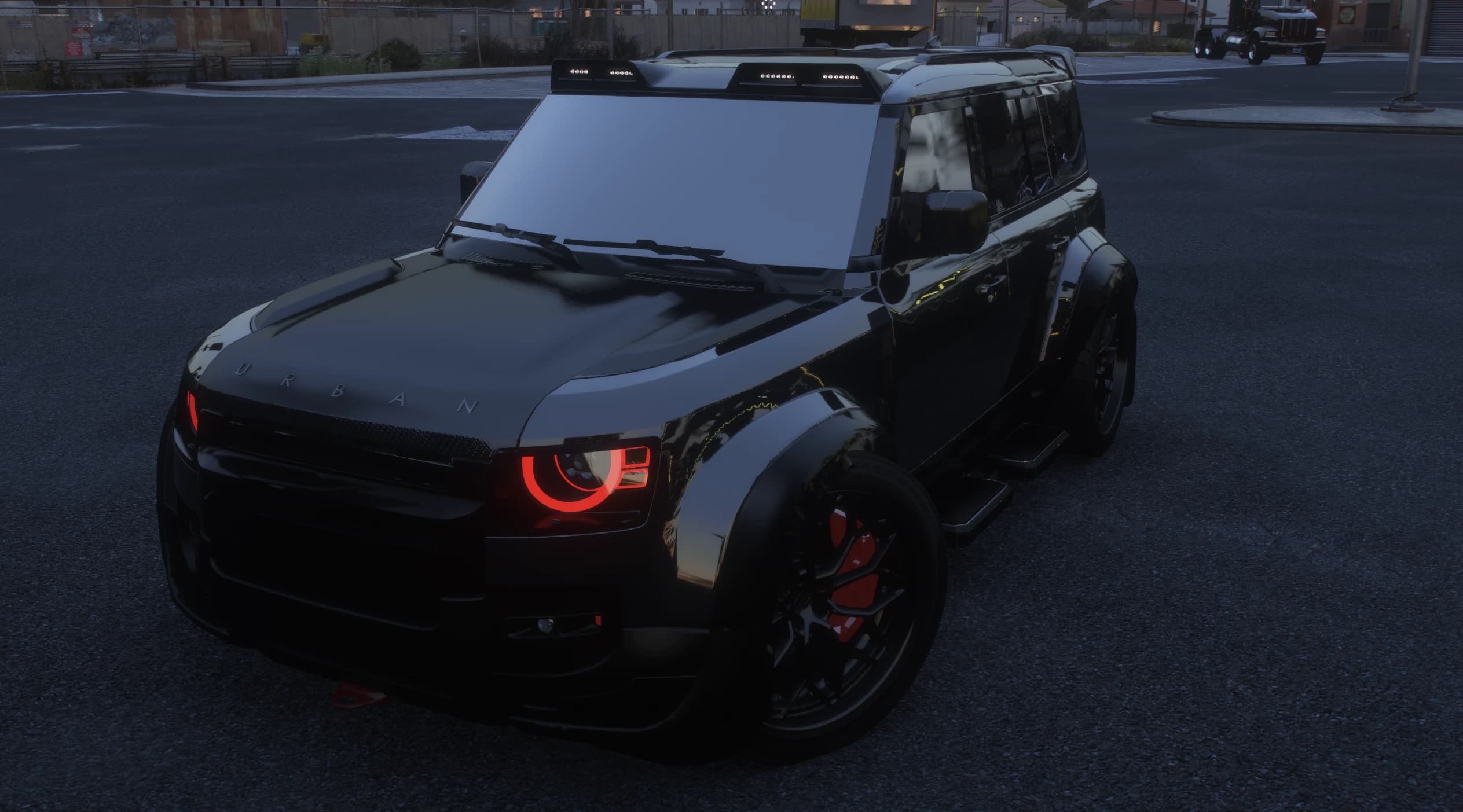 Dusk shot of the all black Defender with URBAN lettering on the bonnet, red glowing halo daytime lights and the roof visor with LED pods