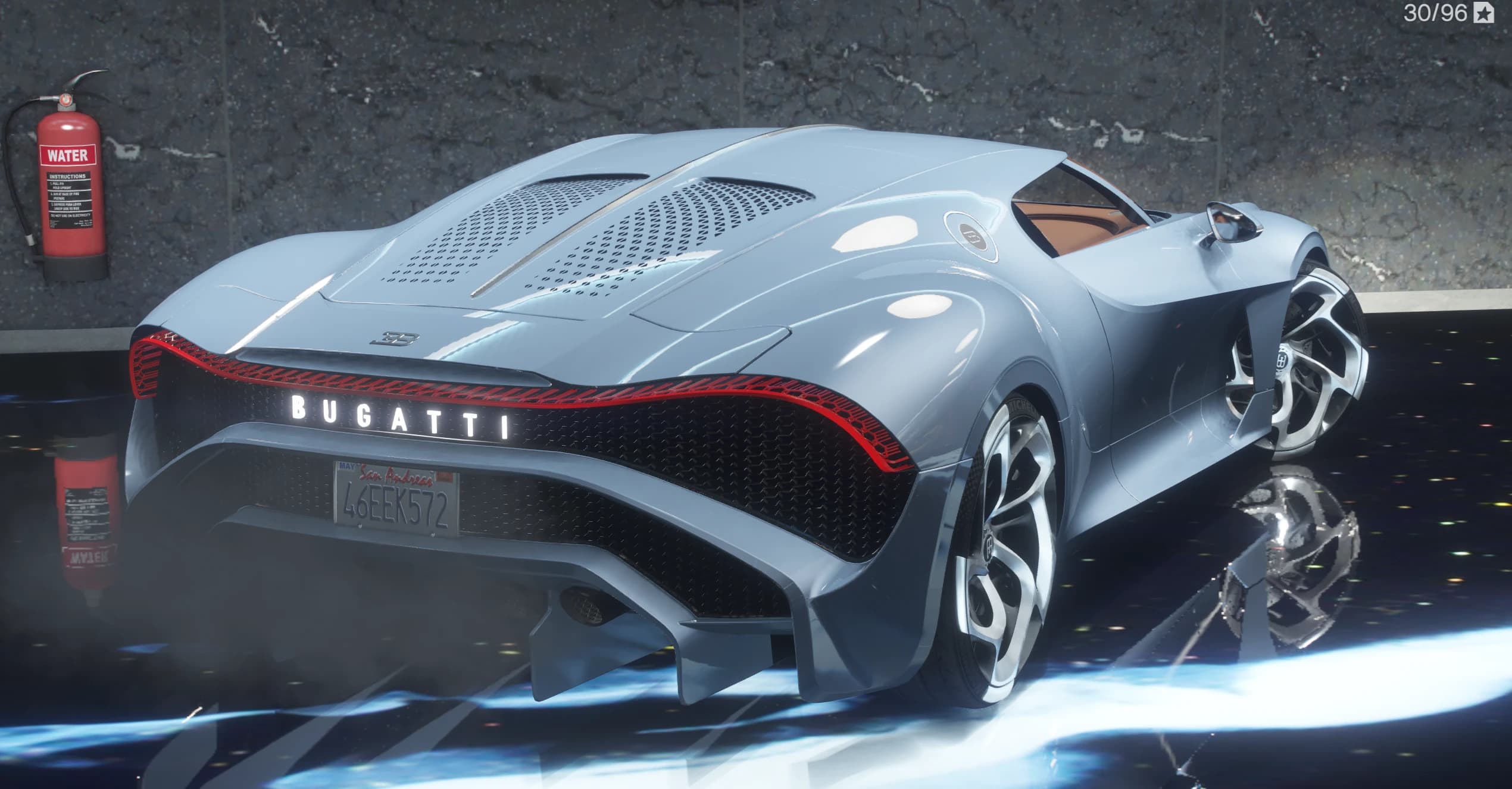 Rear three-quarter of the grey-blue La Voiture Noire with the backlit BUGATTI script across the tail, a red LED light bar and quad tailpipes, San Andreas plate 46EEK572 visible