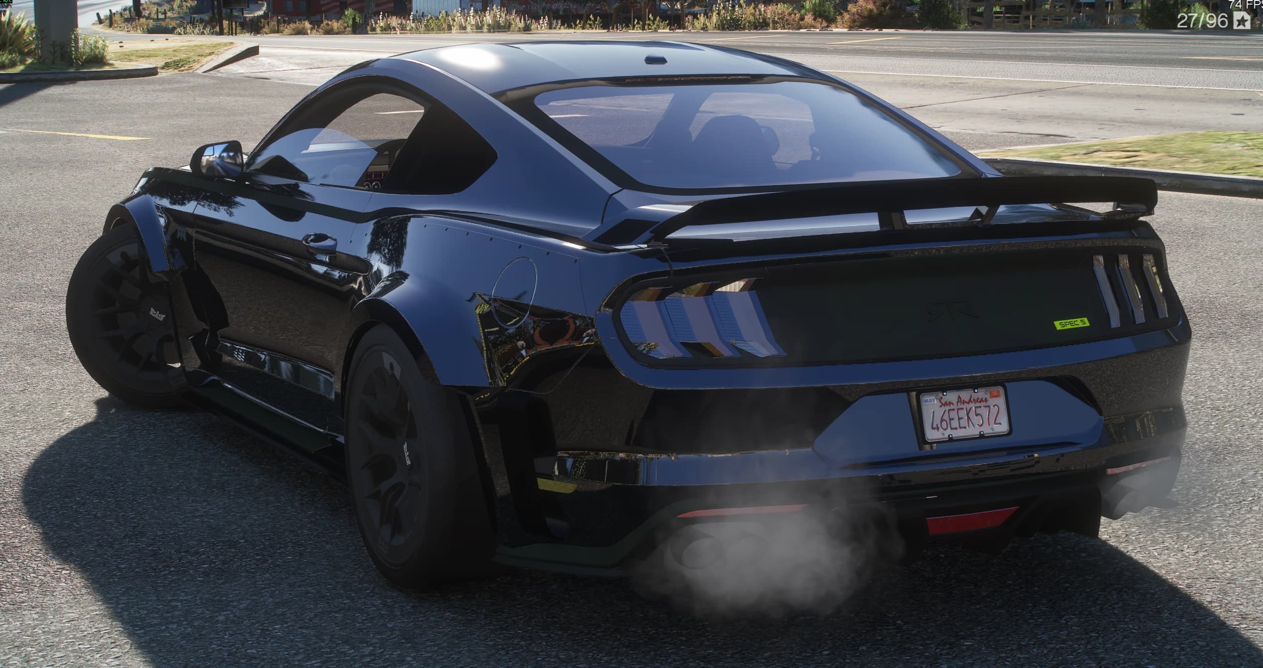 Rear three-quarter of the black Mustang with the tall rear wing, the green SPEC 5 badge on the tail panel, the RTR lettering, the tri-bar lights and smoke coming off the quad exhaust