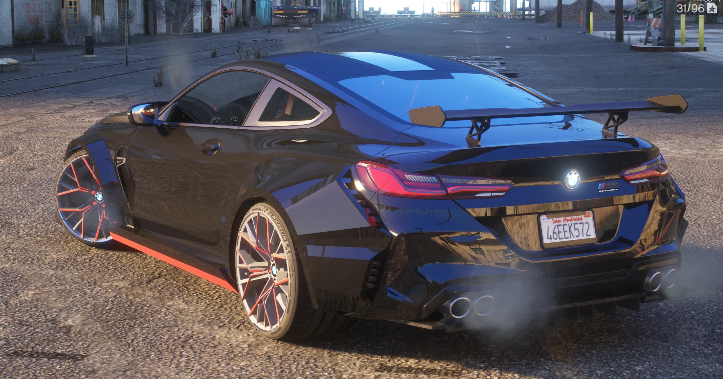 Rear three quarter view with the carbon GT wing on struts, quad exhaust tips in the diffuser and the M8 Competition badge by the San Andreas plate