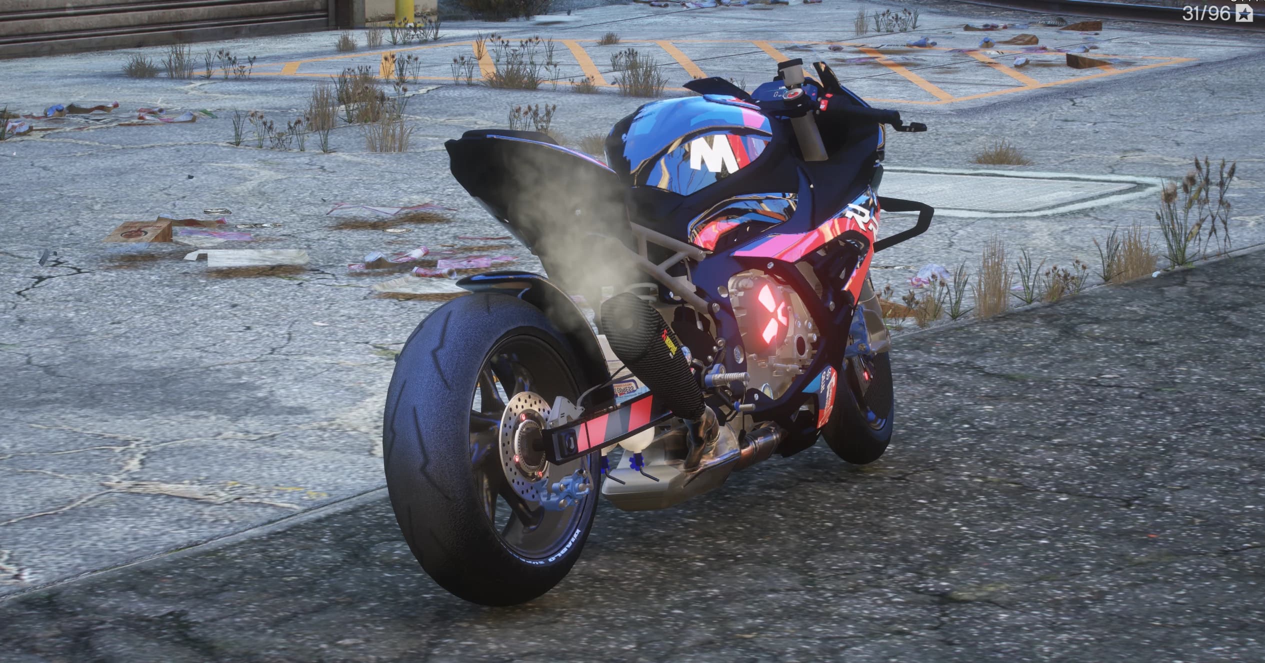 Rear three quarter view showing the extended swingarm, carbon Akrapovic exhaust and the lit red cross emblem on the clutch cover