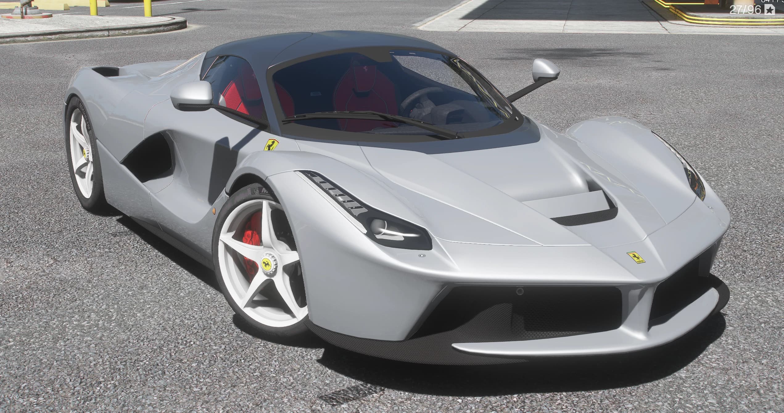 Silver Ferrari LaFerrari in front three-quarter view on a city street, with the red cabin visible through the glass, white five-spoke wheels and red brake calipers