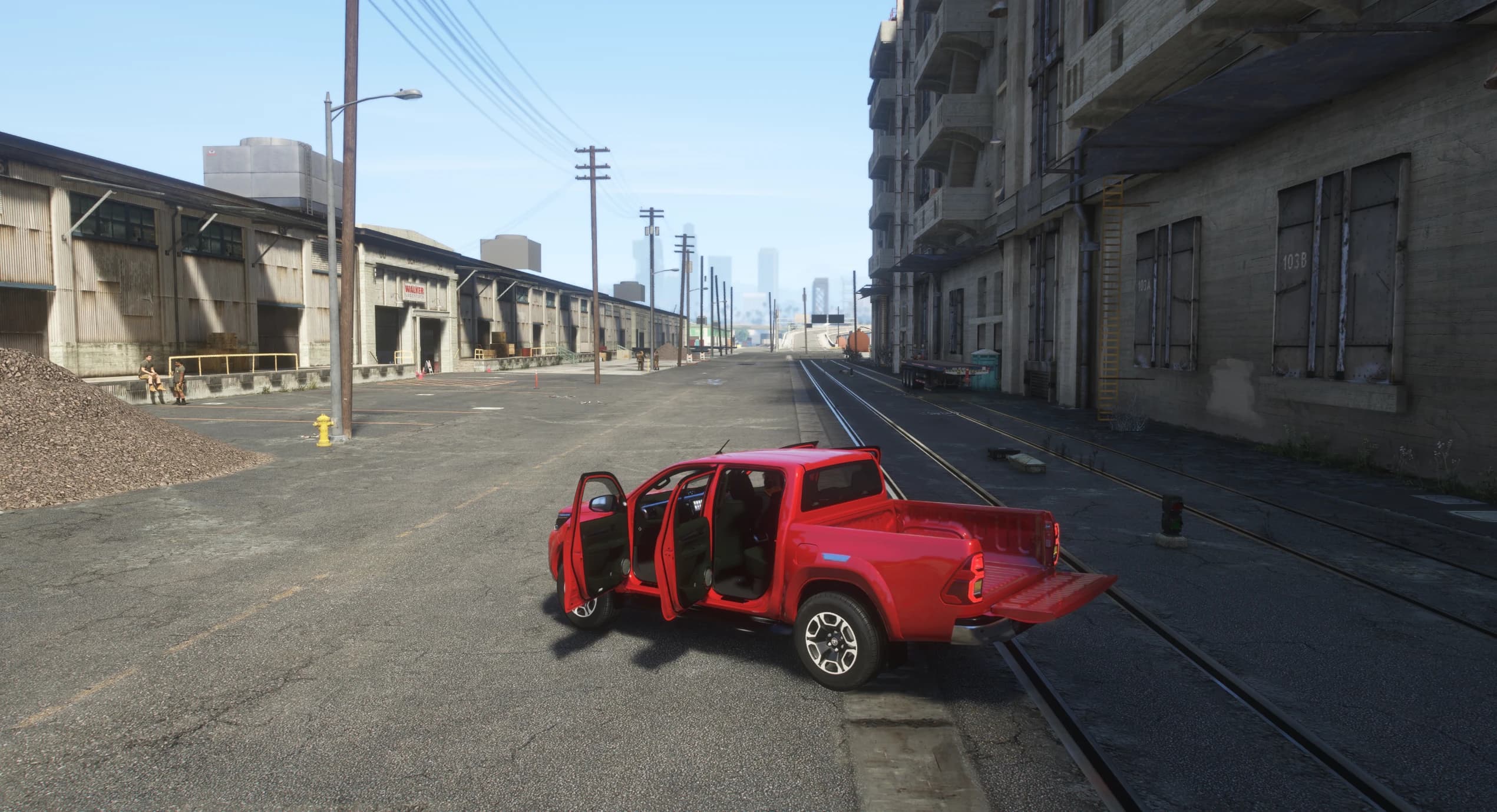 The red Hilux parked on a dockside street with all four doors open and the tailgate dropped, showing the dark cabin