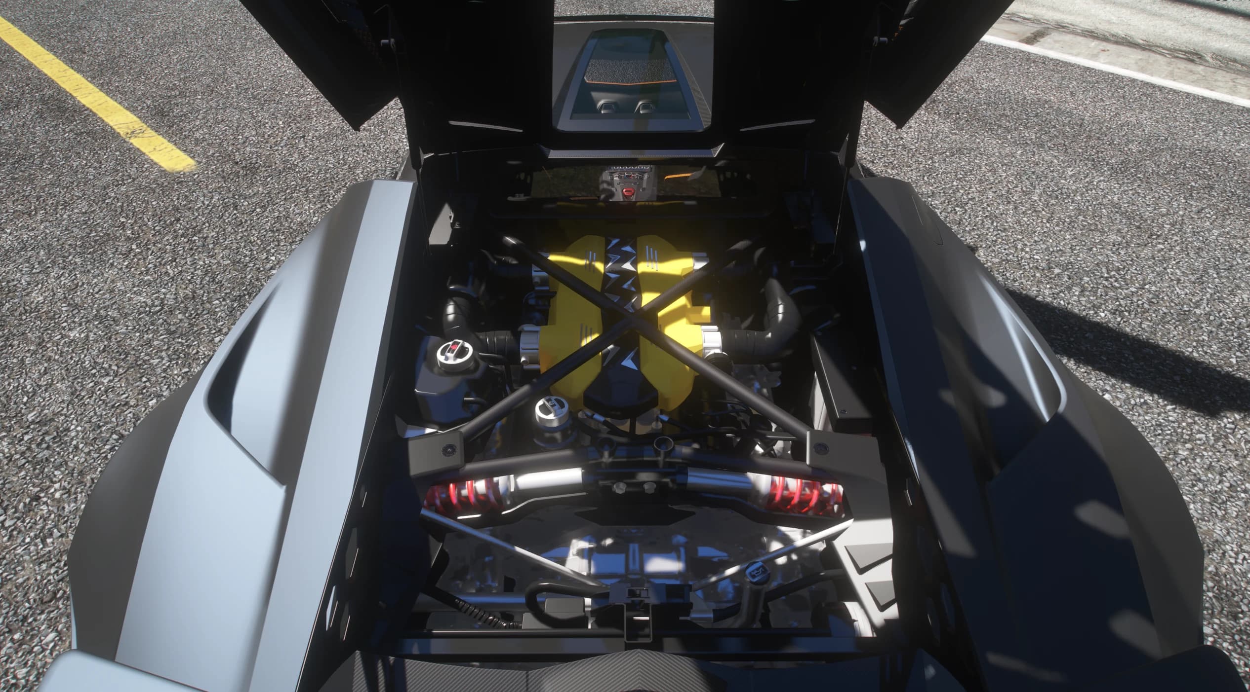Open engine bay with the yellow intake plenums of the V12, a carbon X brace across the bay and red coilover springs in view