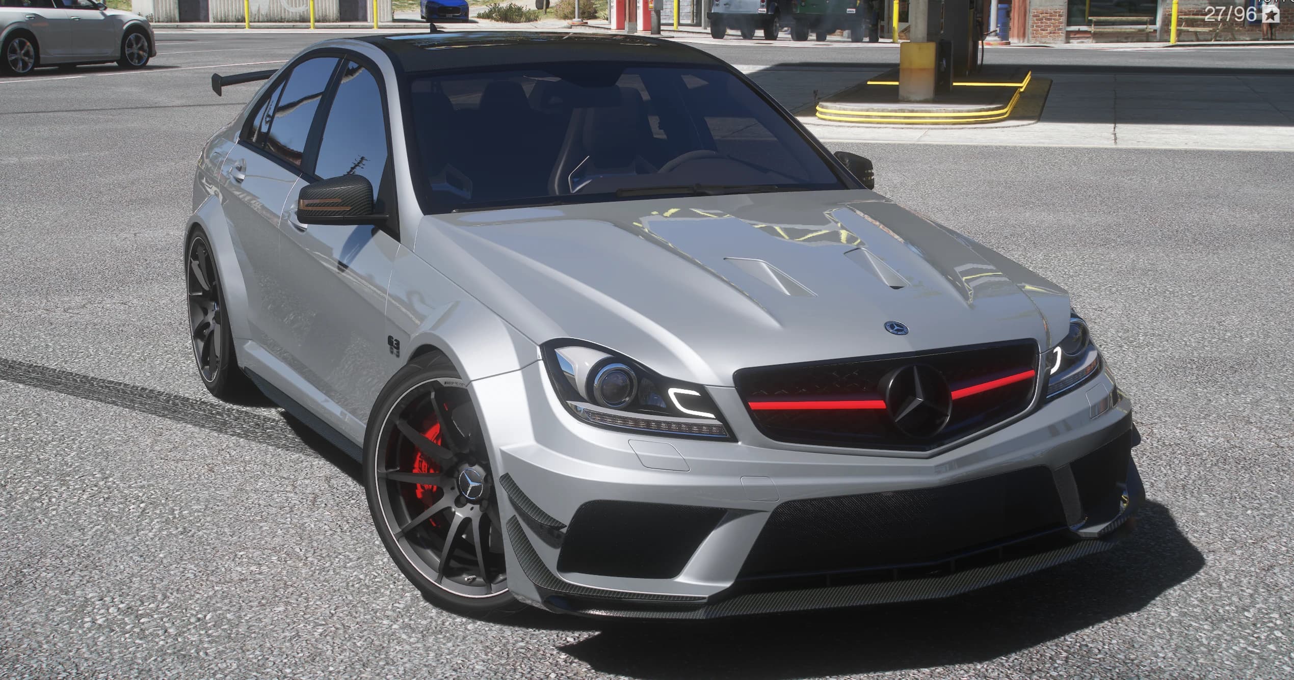 Silver Mercedes-Benz C63 AMG W204 Black Series widebody sedan, front three-quarter view with the vented wide arches, the carbon splitter, the dark mesh grille with its red bar and black wheels over red brake calipers