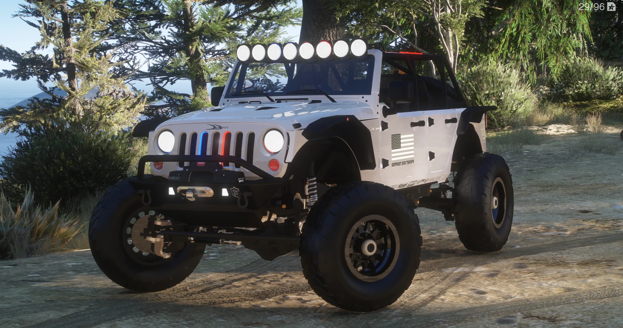 The same white Wrangler in daylight on a dirt trail, front three-quarter, showing the roof light bar, winch bumper and red-and-blue grille lights