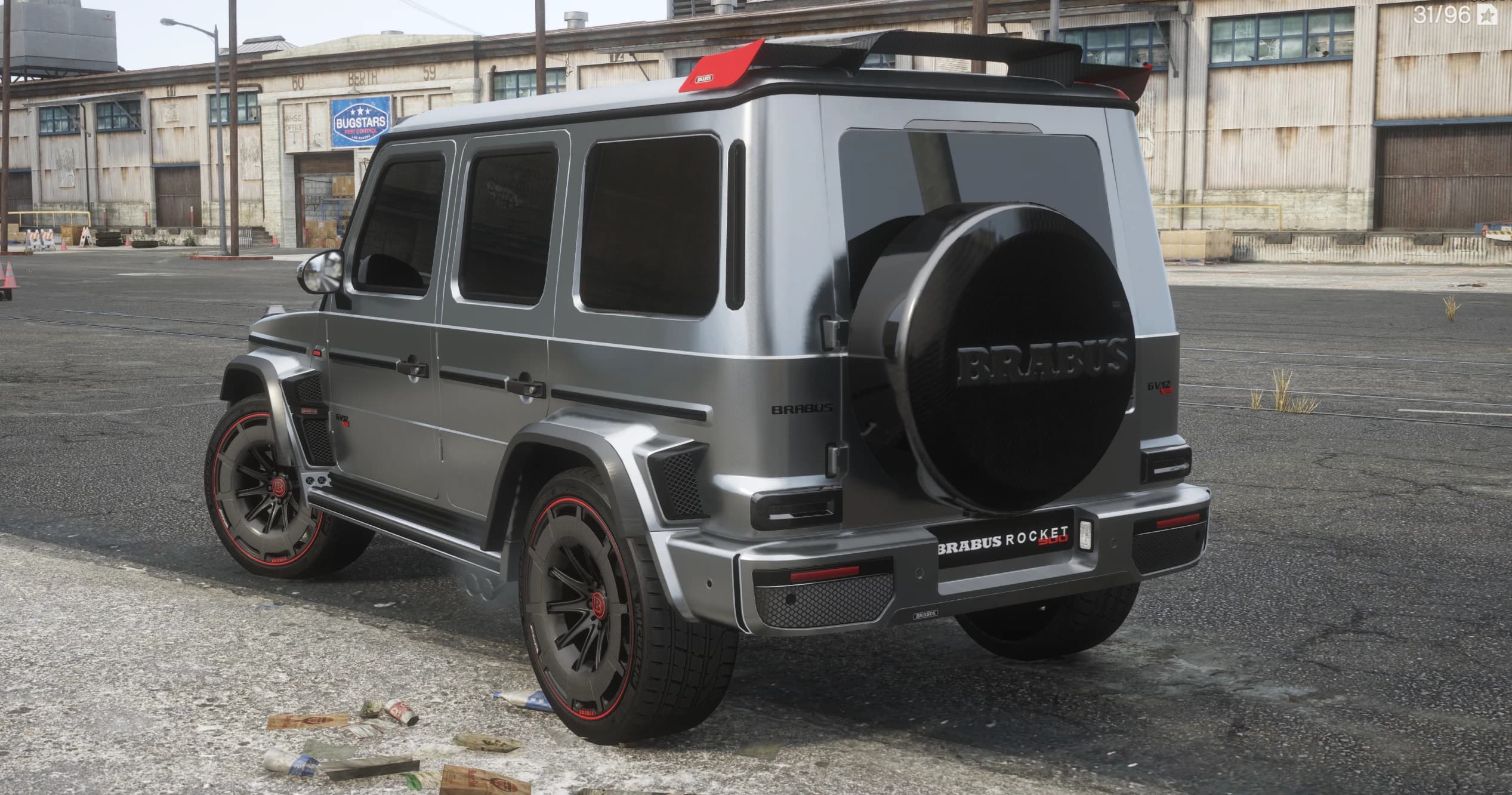 Rear three quarter view showing the carbon spare wheel cover with Brabus lettering, the red tipped roof spoiler, GV12 badges and red rimmed wheels