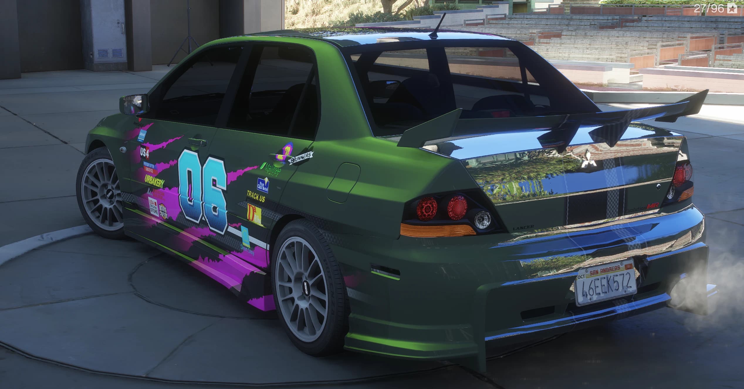 Rear three-quarter of the green Evo VIII showing the tall carbon rear wing, the Evolution MR boot badge and smoke coming out of the exhaust, with the number 06 livery running down the side
