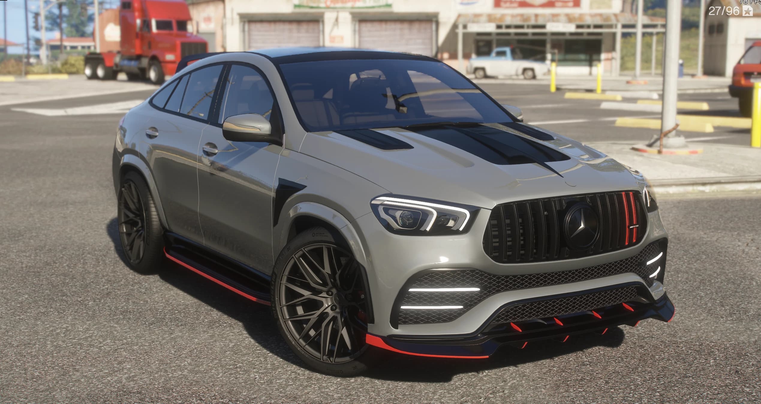 Grey Mercedes-Benz GLE 53 AMG coupe with the Larte Design kit, front three-quarter view outside a rural garage, showing the red accents on the front lip and side skirts, the vertical-slat AMG grille and the black multi-spoke wheels