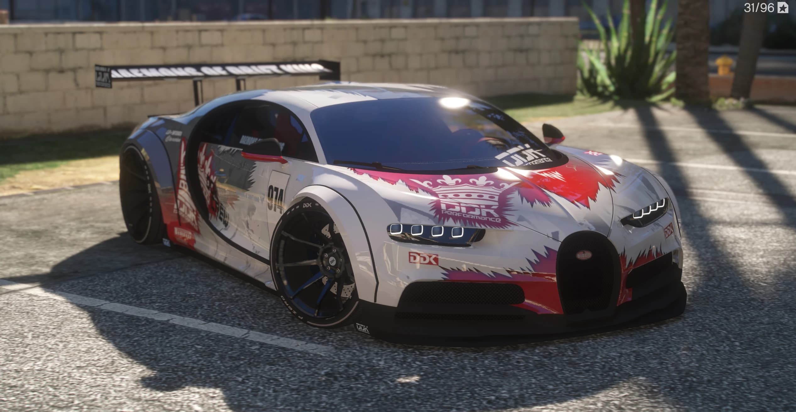 Front three quarter view of the widebody Bugatti Chiron in the white, red and pink DDK Performance drift livery with race number 974 and a straight GT wing over the tail