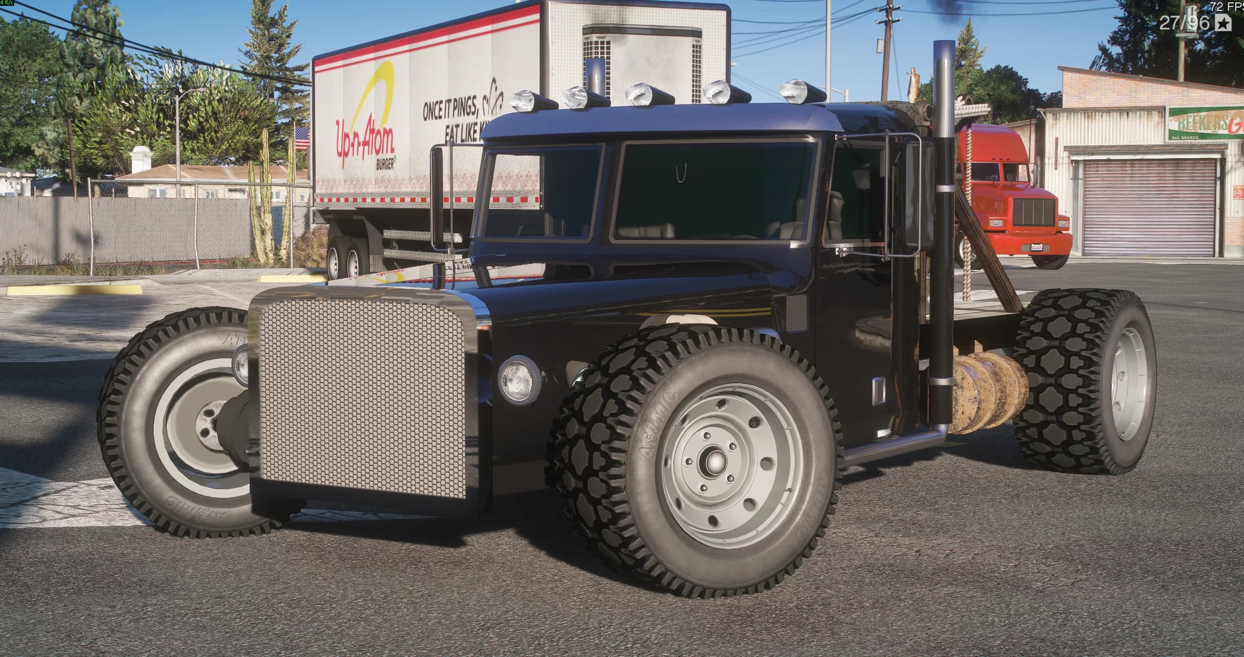 Black Peterbilt Tow-Rod in an industrial yard, front three-quarter view showing the chopped cab, the chrome mesh grille, the five marker lights over the roof, the twin chrome stacks and the chunky off-road tyres