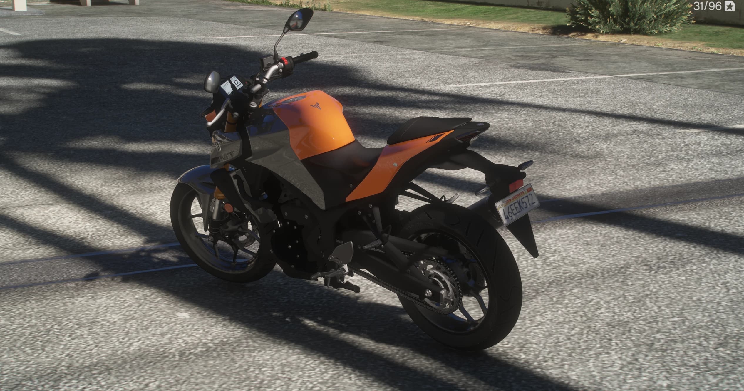 Rear three quarter view of the MT-03 in the palm shade showing the split seat, the chain drive and a San Andreas plate under the tail