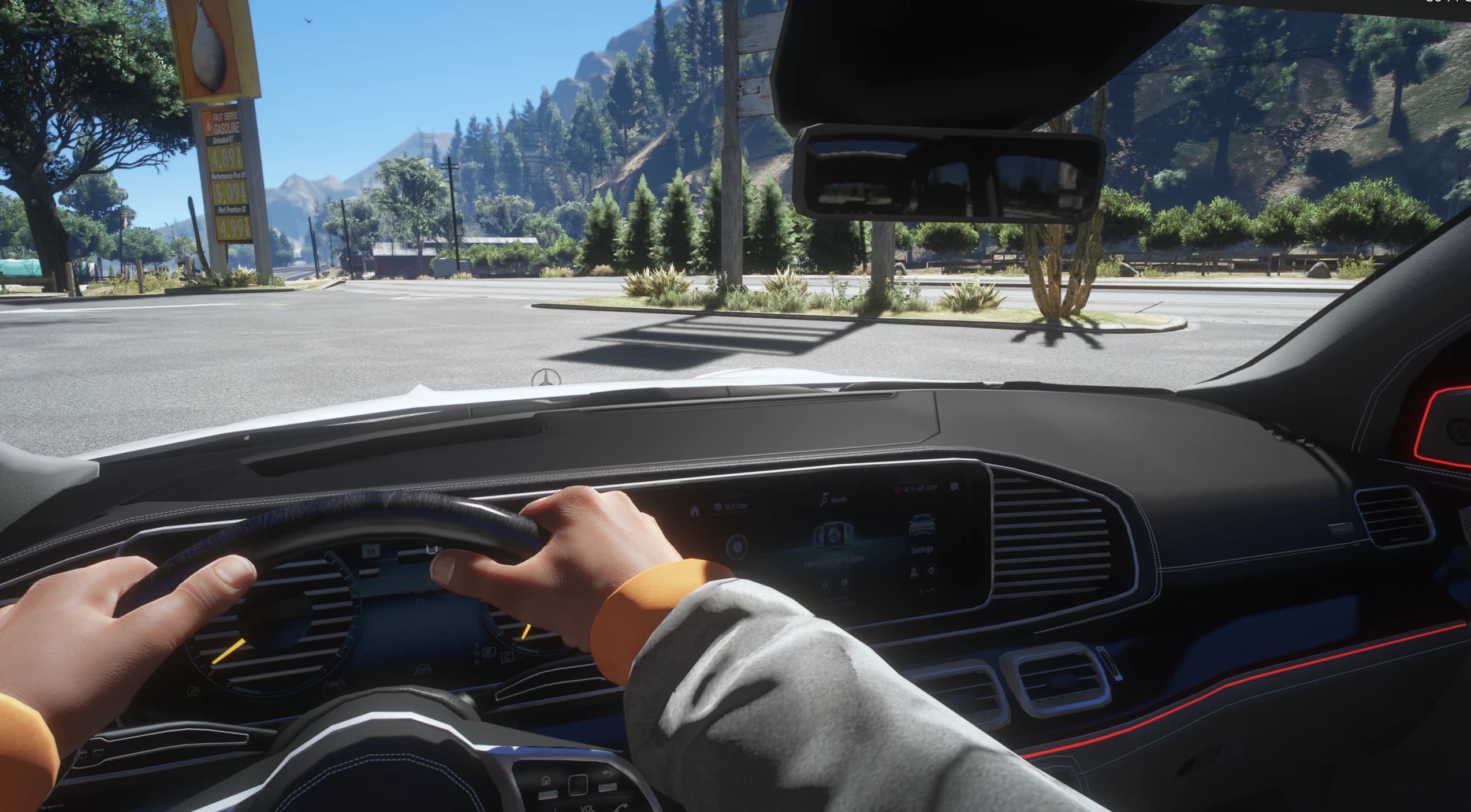 First person driving view over the dual screen dashboard with red ambient lighting, the driver's hands on the wheel and a gas station price sign outside
