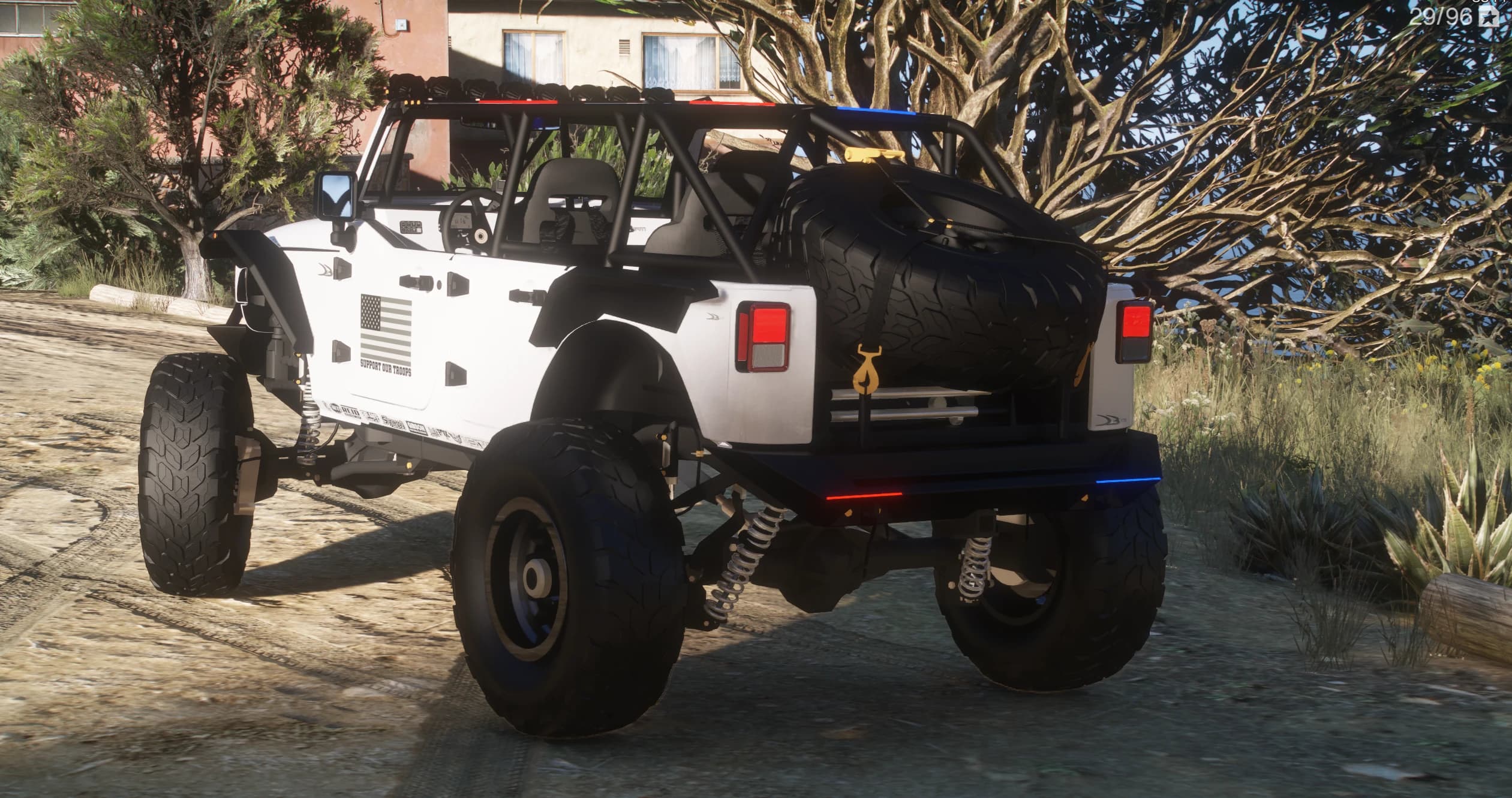 Rear three-quarter of the lifted Wrangler with the exposed roll cage, tailgate-mounted spare wheel and long-travel suspension