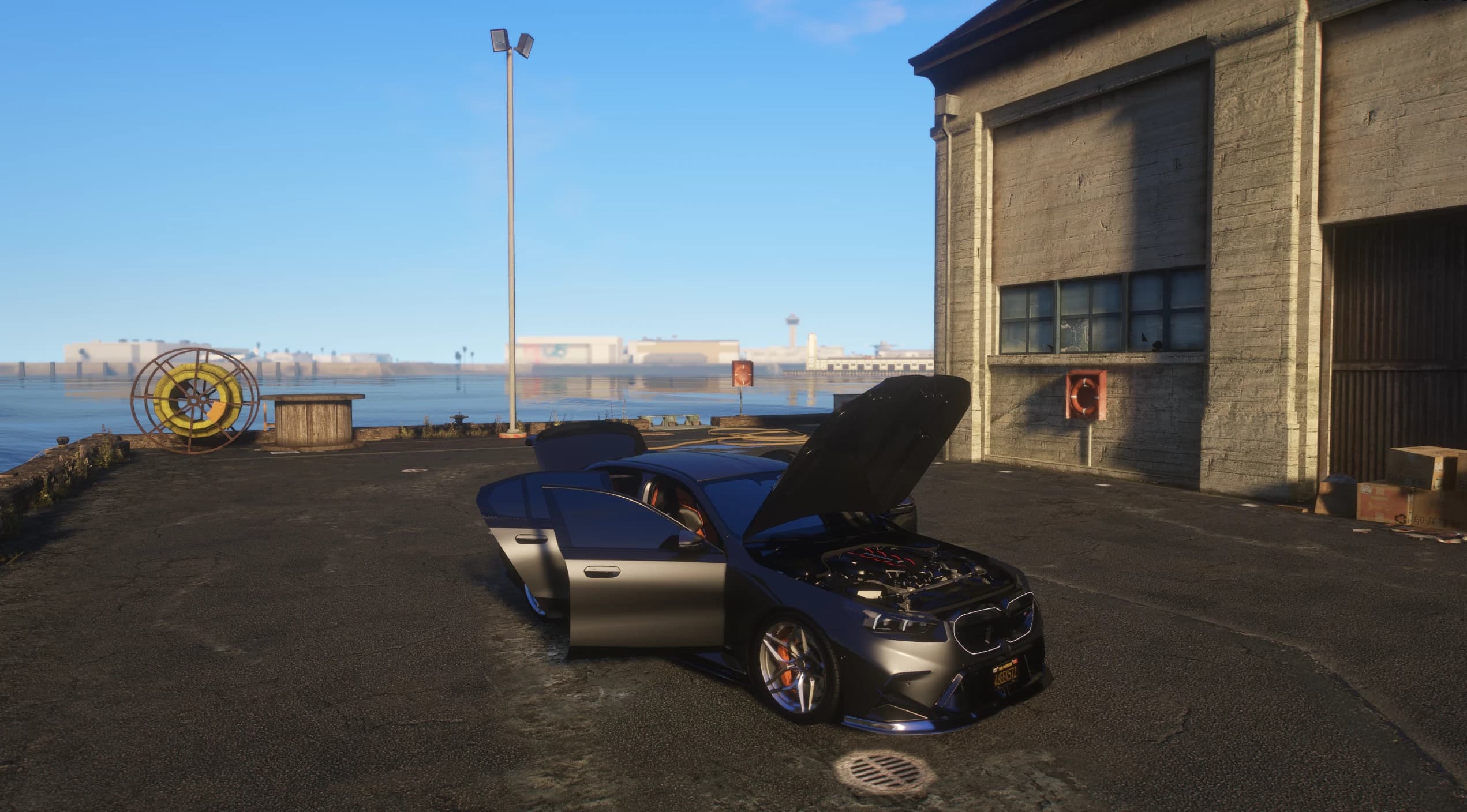 The M5 parked on a dock with doors and bonnet open, showing the fully modelled engine bay and the orange accented interior