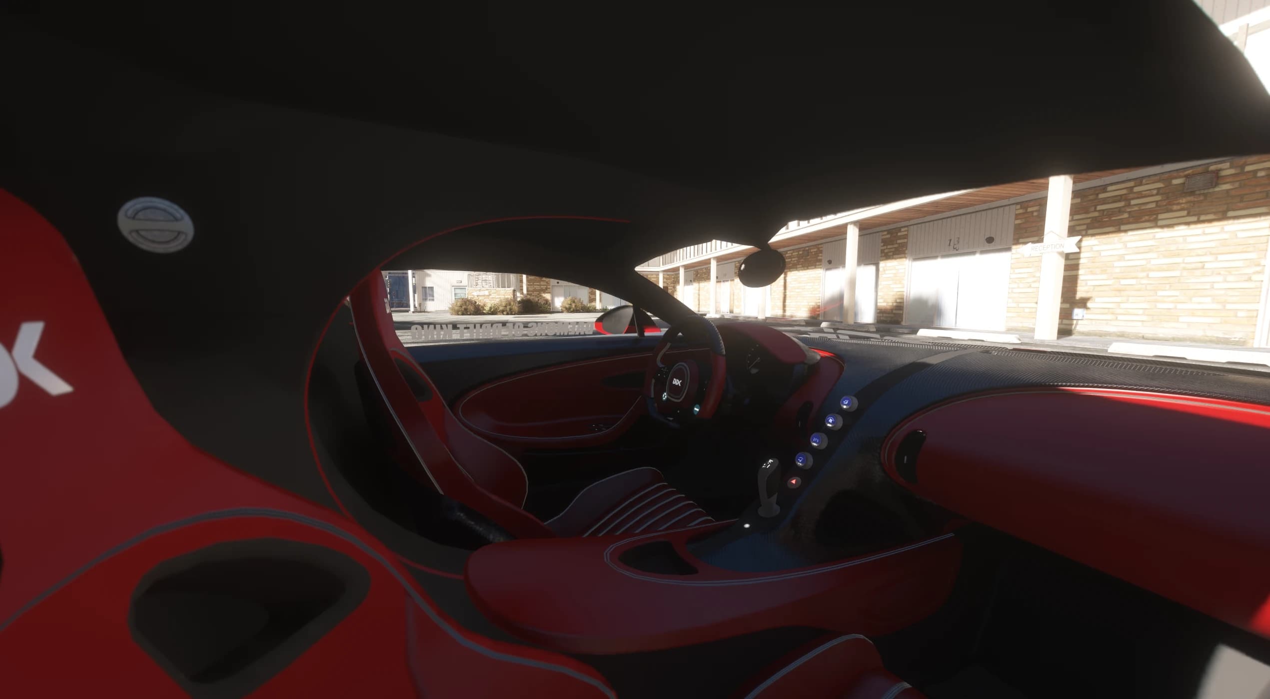 Interior view of the red leather cockpit with striped seats, the DDK logo on the wheel and the blue lit buttons on the carbon centre console