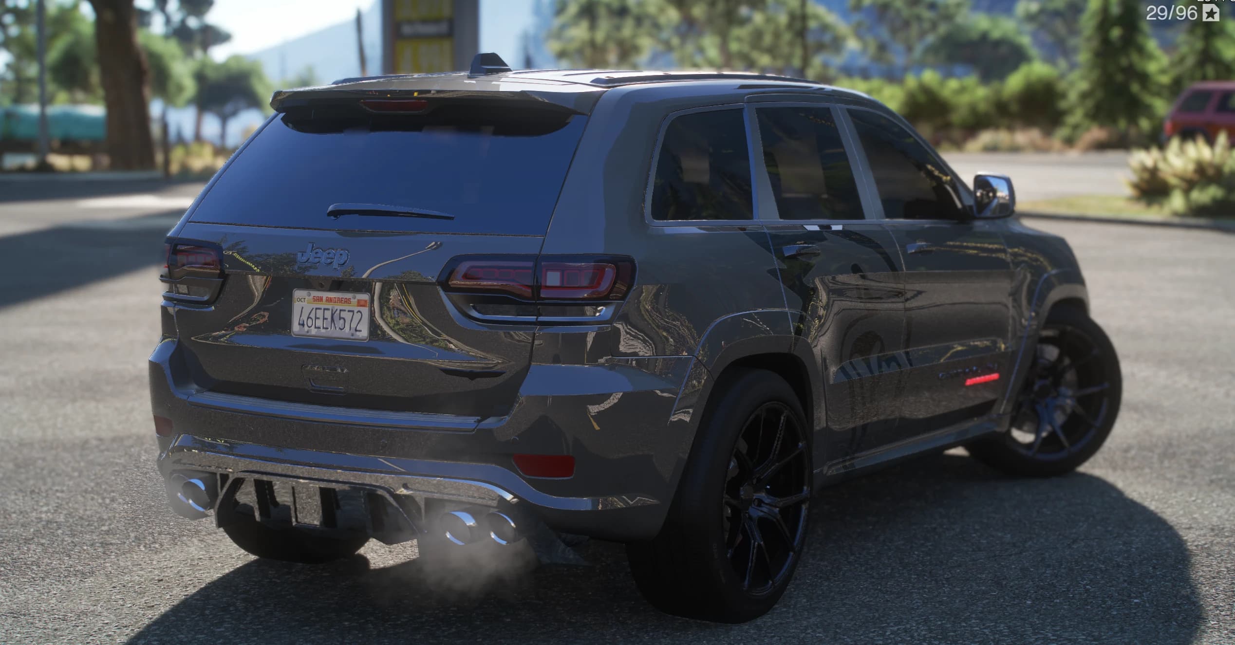 Rear three-quarter of the silver Trackhawk with the Jeep and Grand Cherokee badges, quad exhaust and the lion side graphic