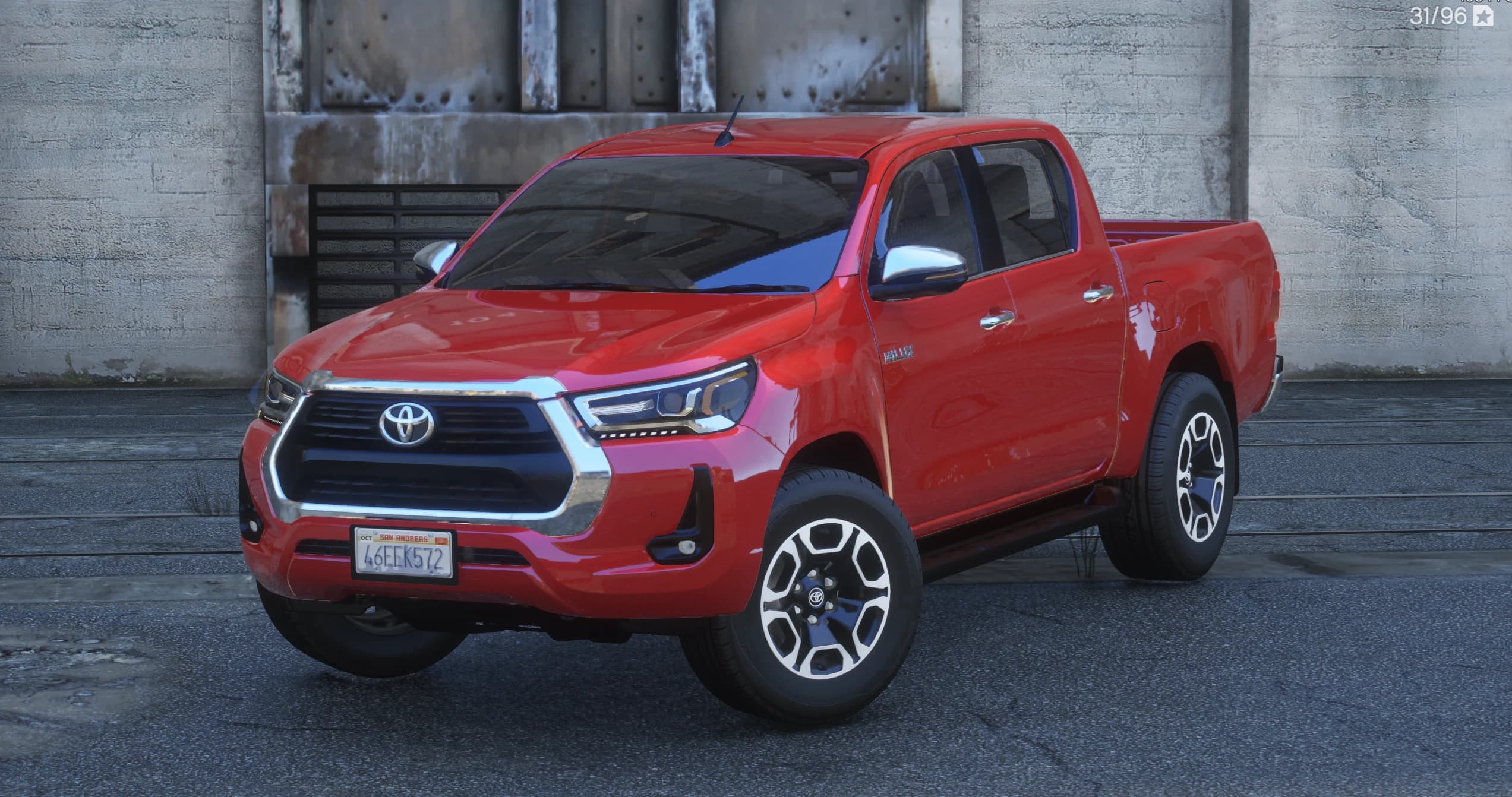 Front three quarter view of the red double cab Hilux with its chrome framed grille, Toyota emblem, LED headlights and two tone alloy wheels