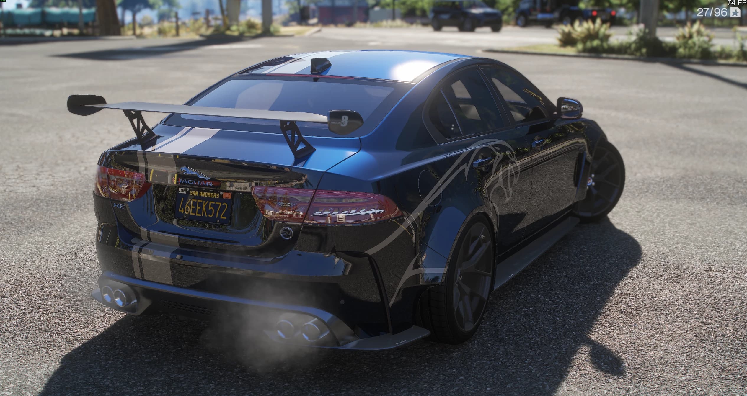 Rear three-quarter of the blue Project 8 with its tall swan-neck rear wing, the white stripe running over roof and trunk, a leaping-jaguar outline graphic on the rear flank and JAGUAR lettering above the plate