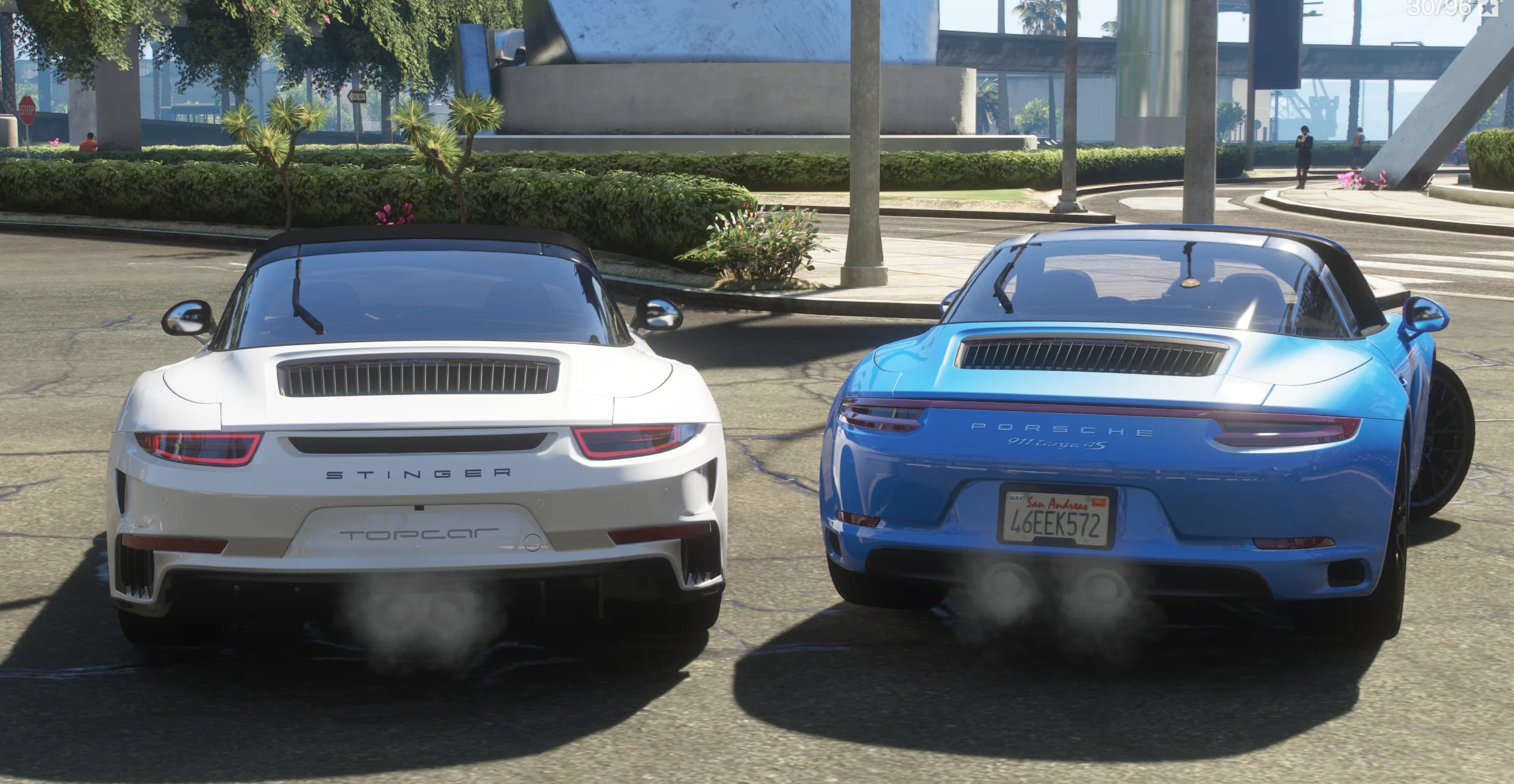 Rear view of both cars with the exhausts smoking: the white Topcar Stinger with STINGER and Topcar lettering on the left, and the blue 911 Targa 4S with the PORSCHE 911 targa 4S script and a 46EEK572 plate on the right