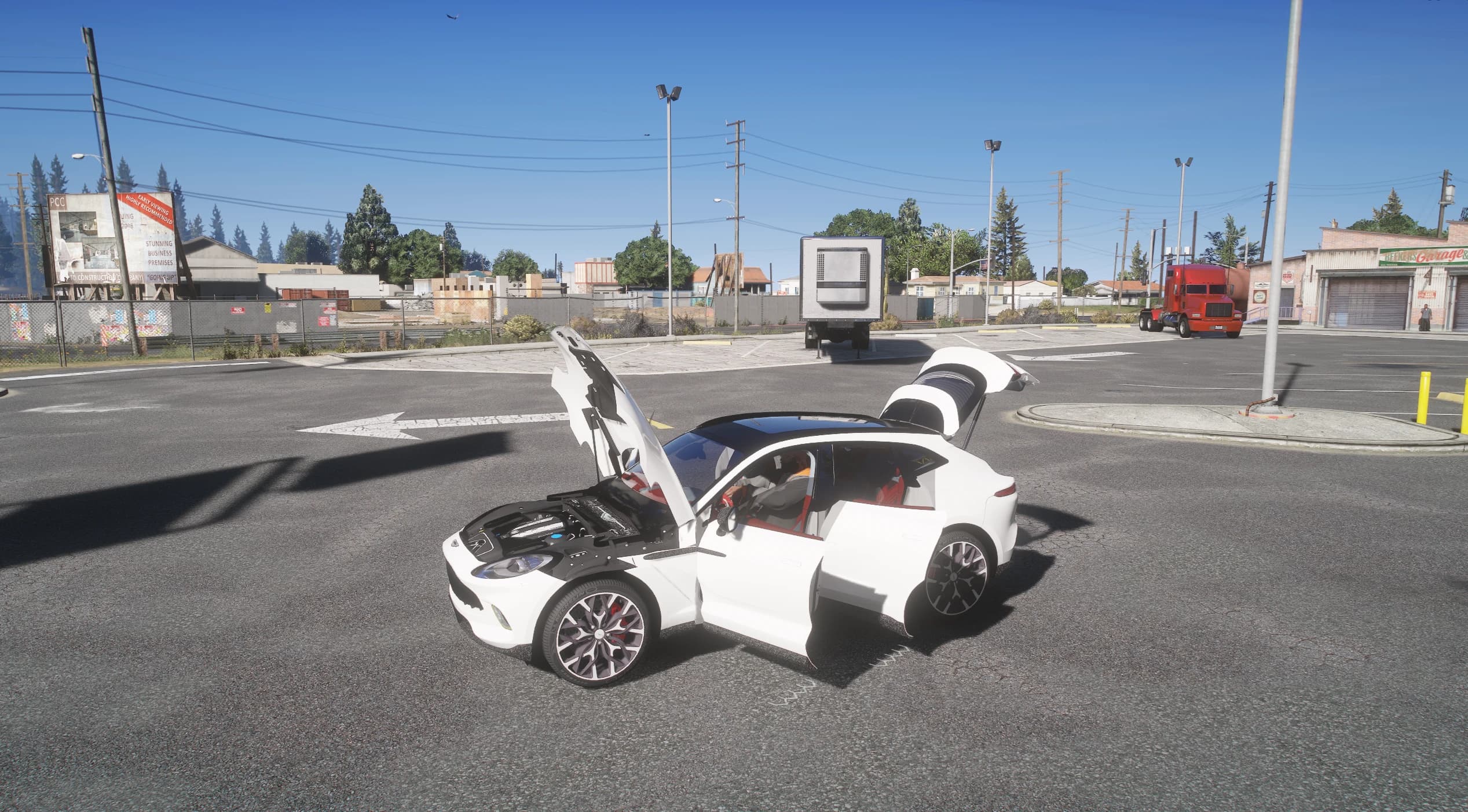 The DBX in a parking lot with the clamshell hood, the two right doors and the tailgate open, showing the modelled engine bay and the red interior, with a red truck by the garage behind