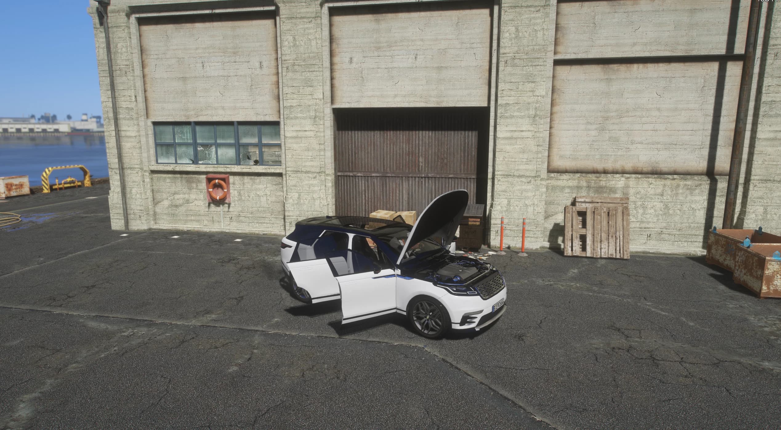 The Velar at a dockside warehouse with the front doors and the clamshell bonnet open over the engine bay