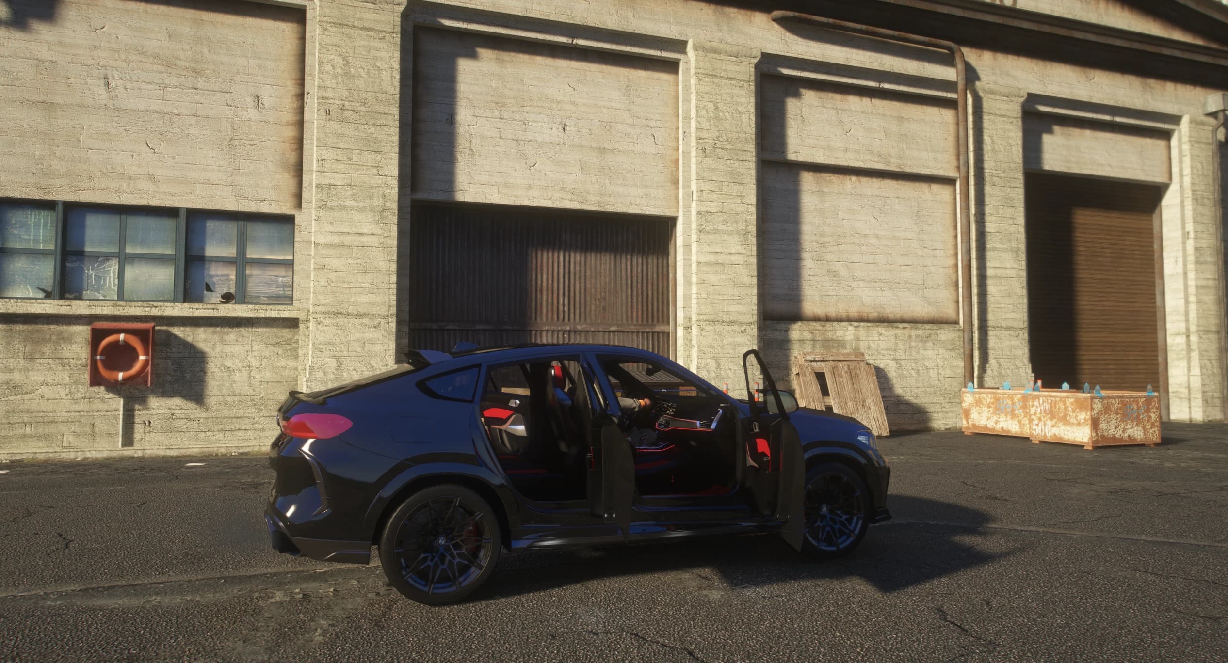 Side view with all four doors open over the red and black interior with red ambient lighting, in front of an old warehouse wall with a life ring