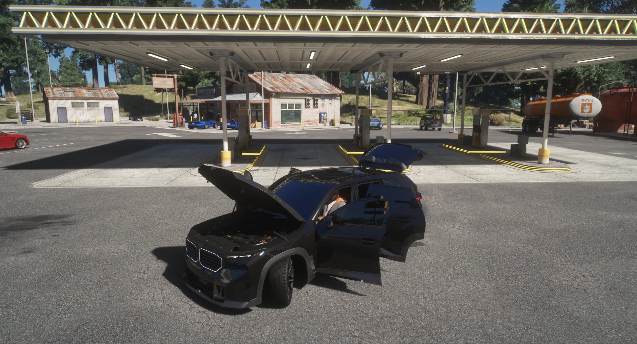 The XM under a gas station canopy with the hood open over the engine bay and all four doors open