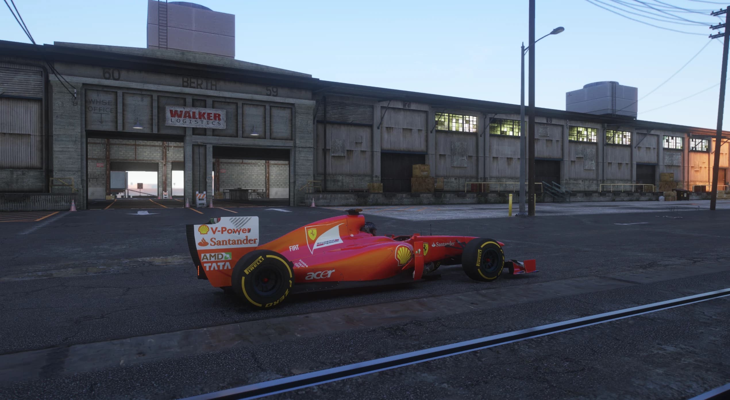 Side view of the red and white 2011 single seater wearing the Santander, Shell and AMD sponsor livery, parked outside the Walker Logistics warehouse