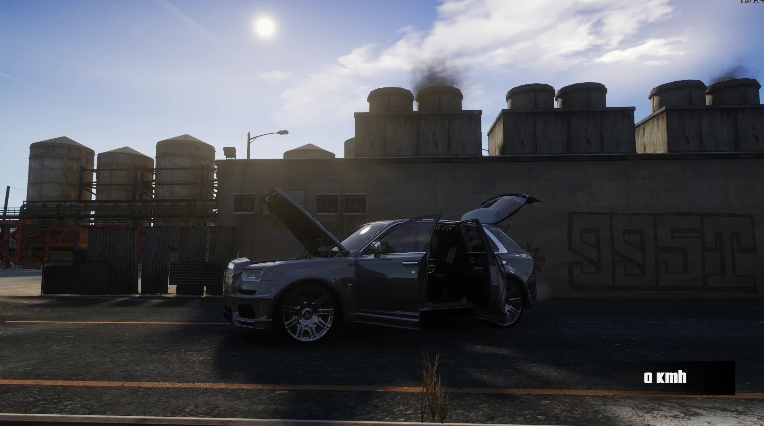 Side view of the grey Cullinan in front of an industrial building with the hood, the doors and the tailgate open, showing the pale leather cabin