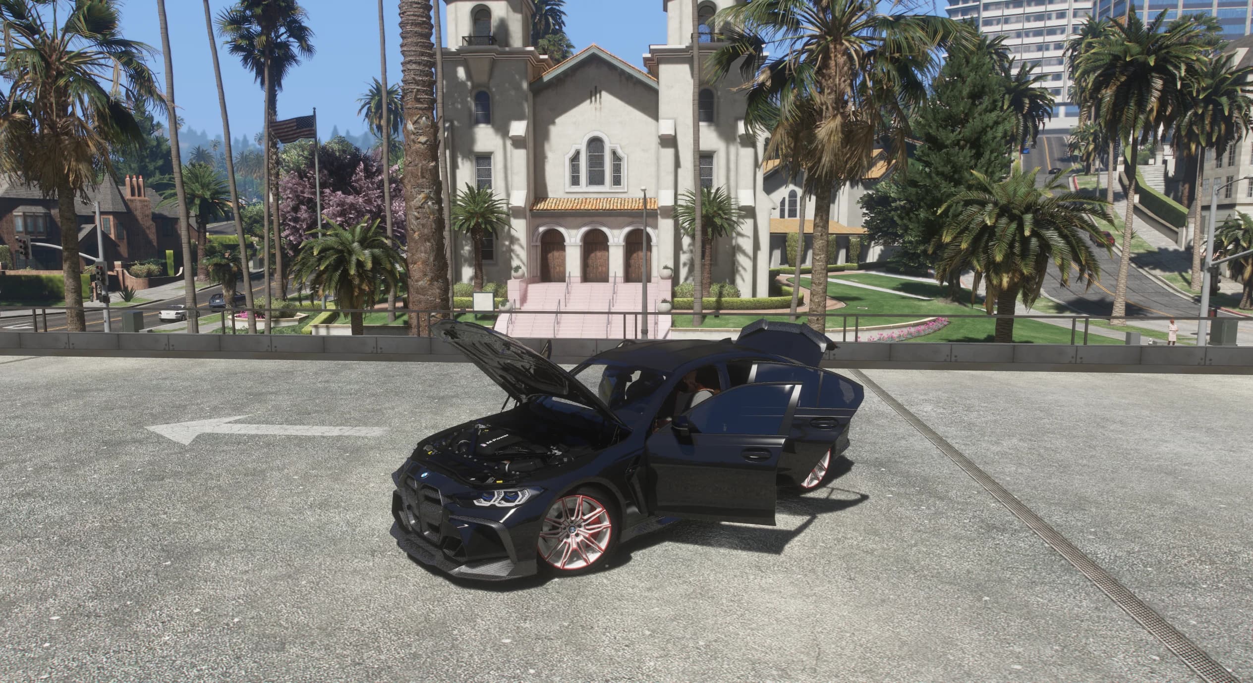 Side view of the M3 with the hood, both doors and the trunk open, exposing the detailed M Power engine bay in front of a Vinewood church