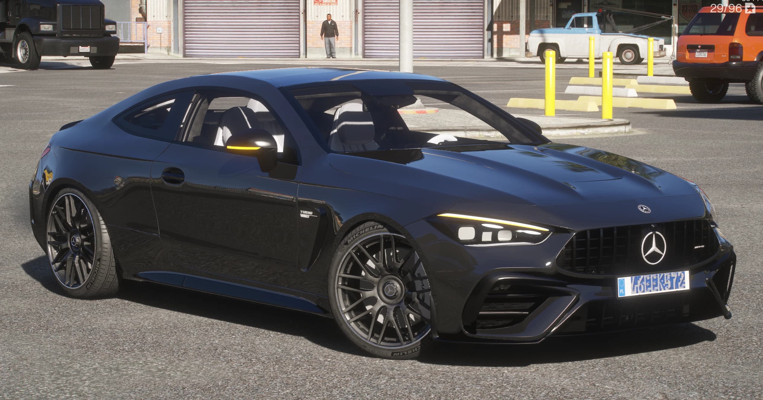 Dark Mercedes-AMG CLE 53 coupe, front three-quarter view with the AMG star grille, split LED headlights and multi-spoke wheels, parked outside a garage