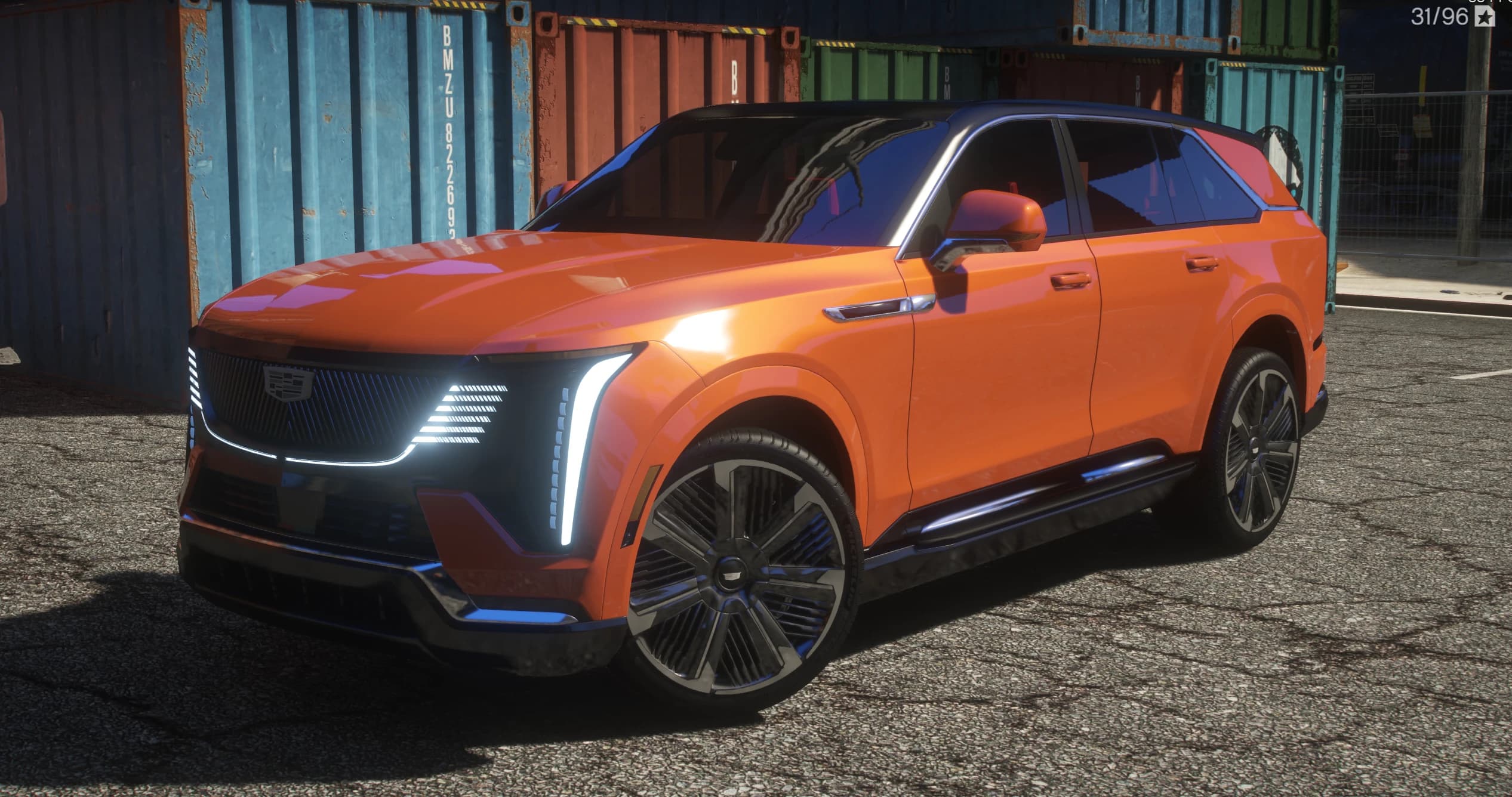 Front three quarter view of the orange Escalade IQ with its lit grille pattern, vertical LED blades and black roof
