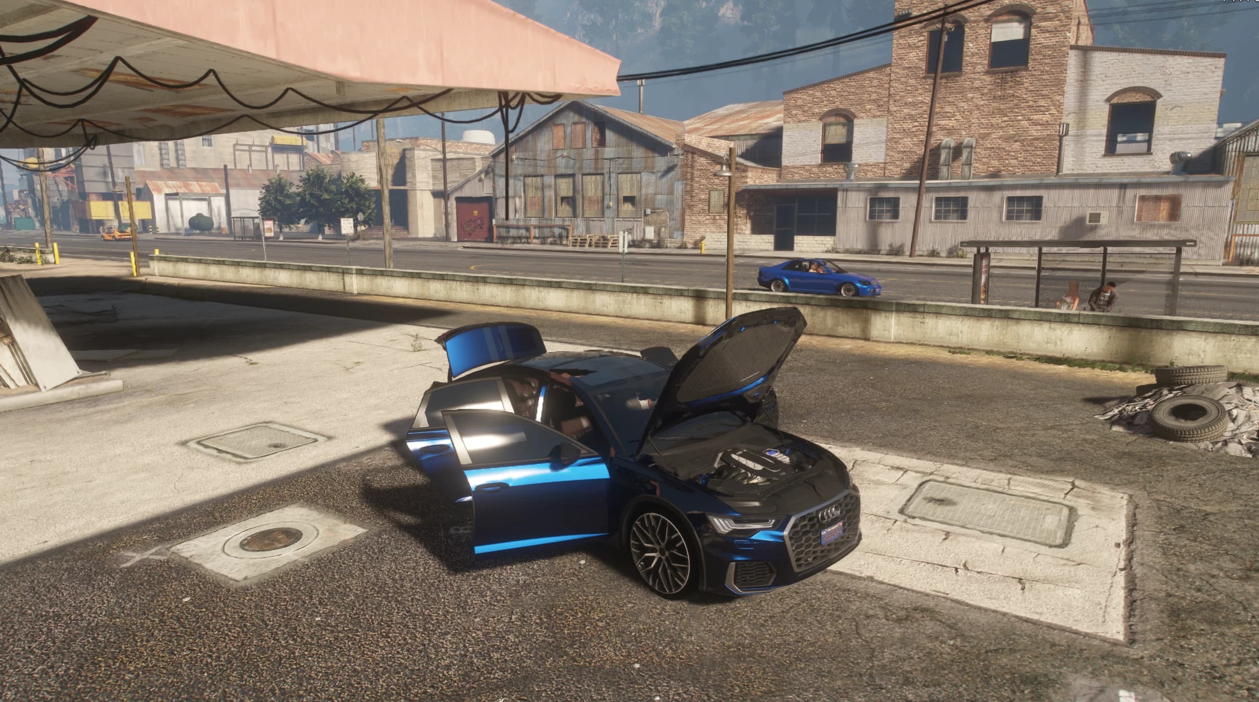 The A6 at an old gas station with the hood, doors and boot open showing the engine bay, with a blue sports sedan passing on the street