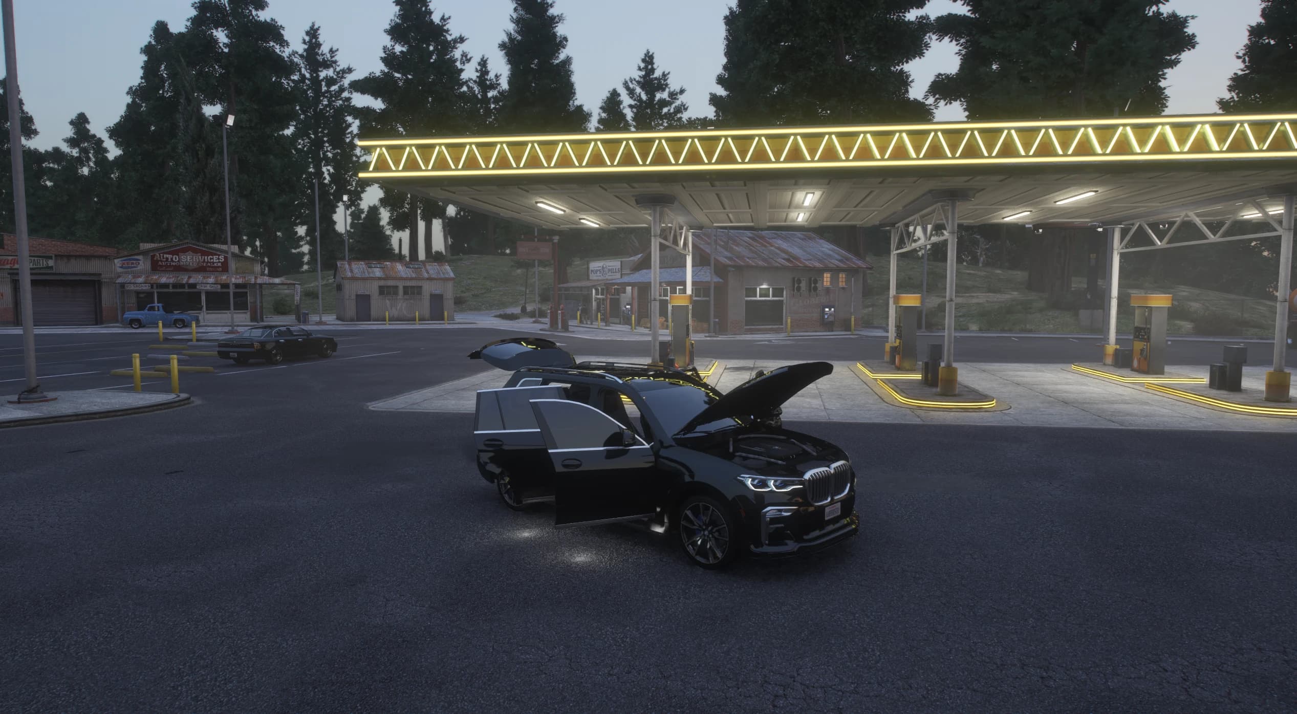 Wide dusk shot under a lit gas station canopy with the X7's hood, doors and split tailgate open