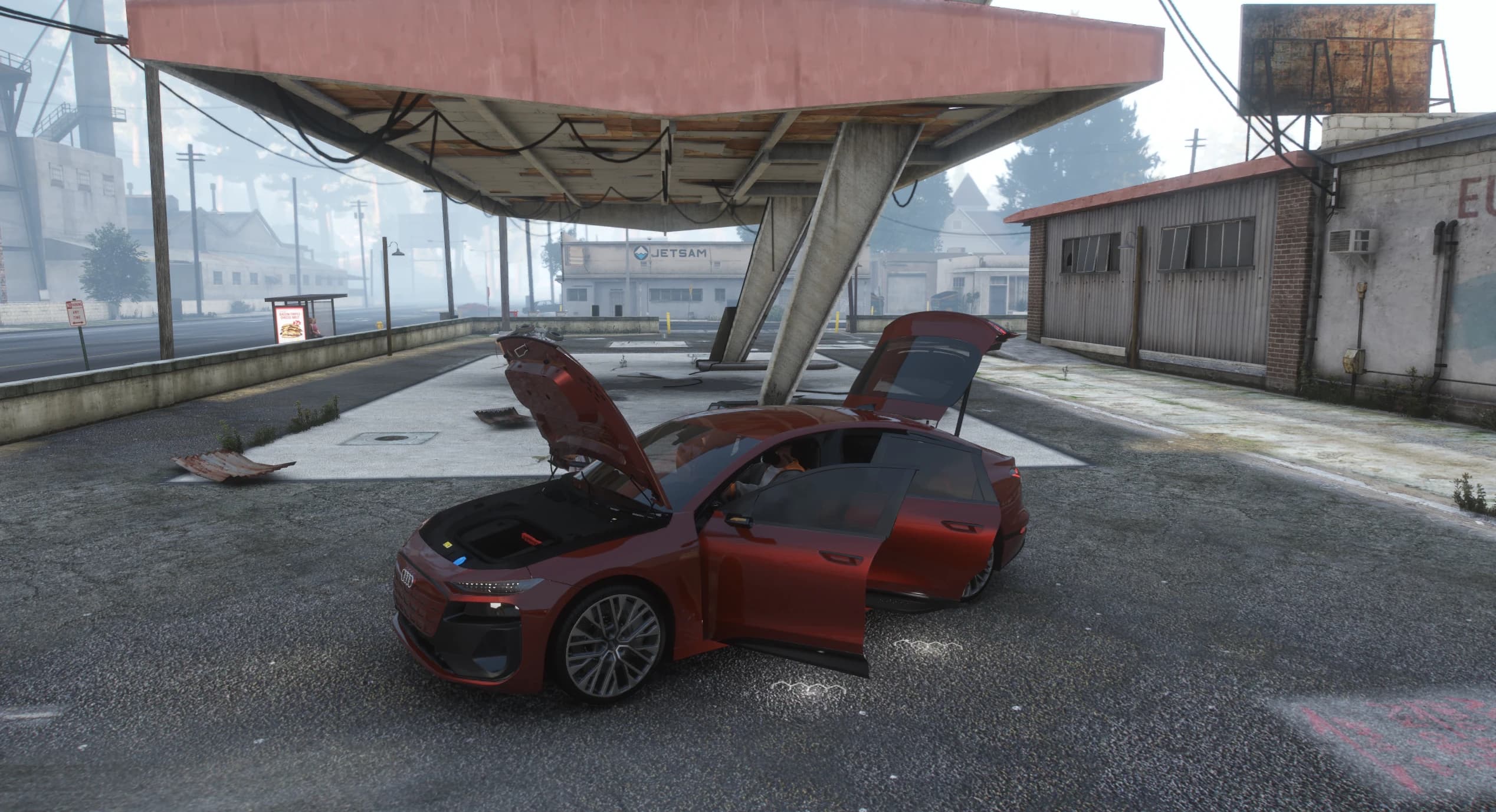 The A6 e-tron under a decayed gas station canopy with the hood, doors and liftback hatch open showing the front compartment