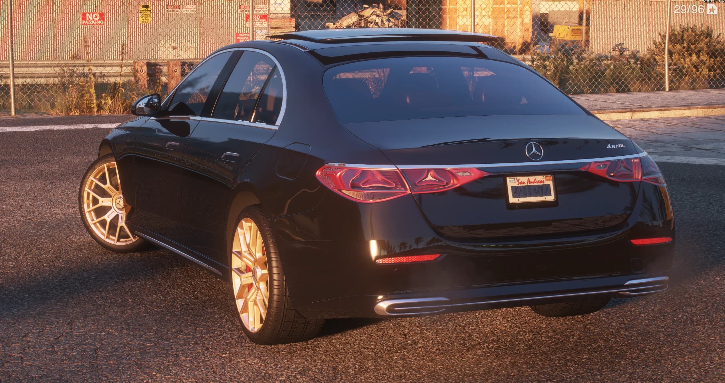Rear three-quarter of the black E350 with the 4MATIC badge, connected LED taillights and a San Andreas plate, beside a chain-link fence