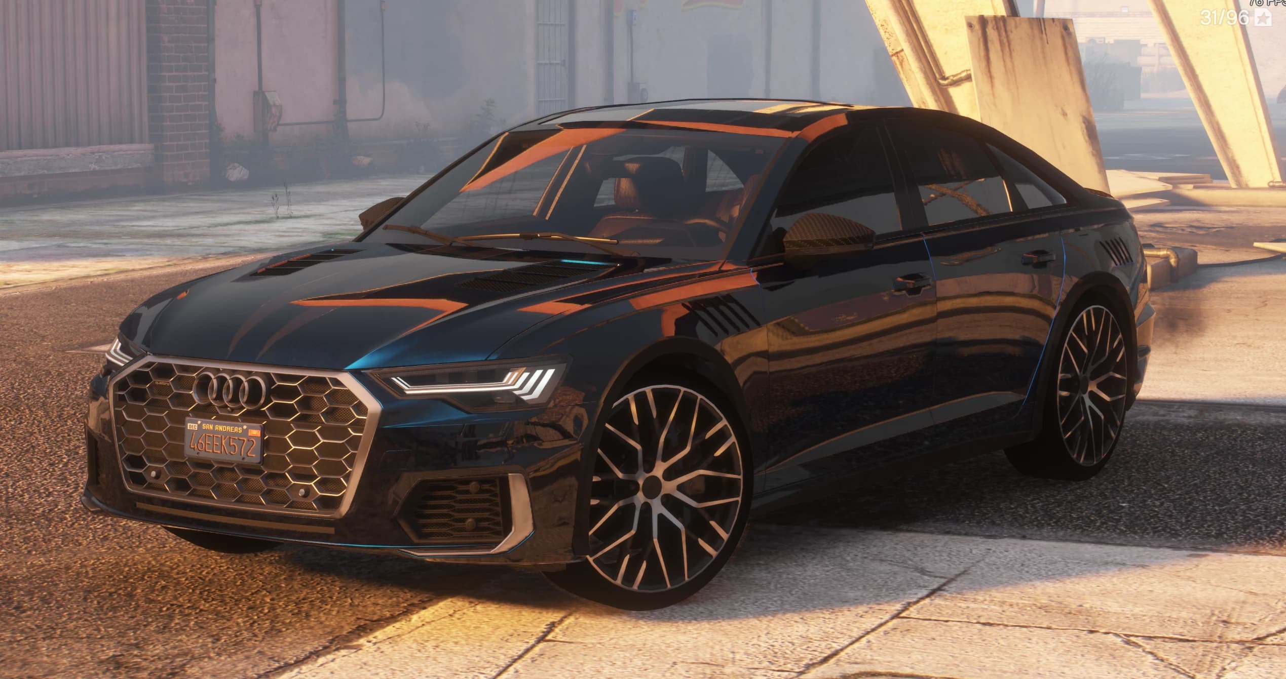 Front three quarter view of the dark blue Audi A6 with the honeycomb grille, vented hood, fender vents and machined Y spoke wheels