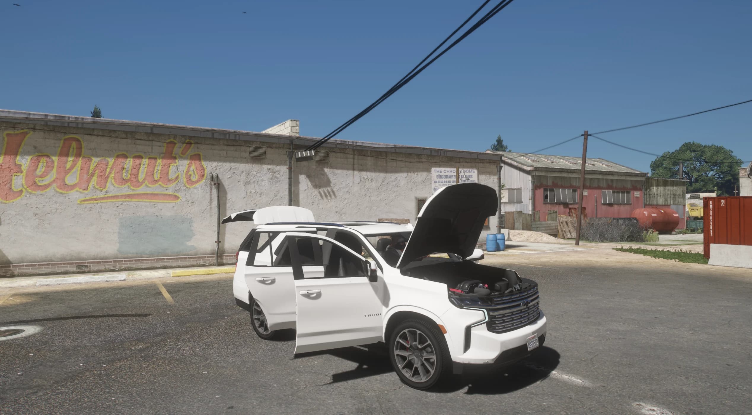 The Tahoe parked by a wall with the Helmut's mural, with the hood, doors and tailgate all open showing the engine bay