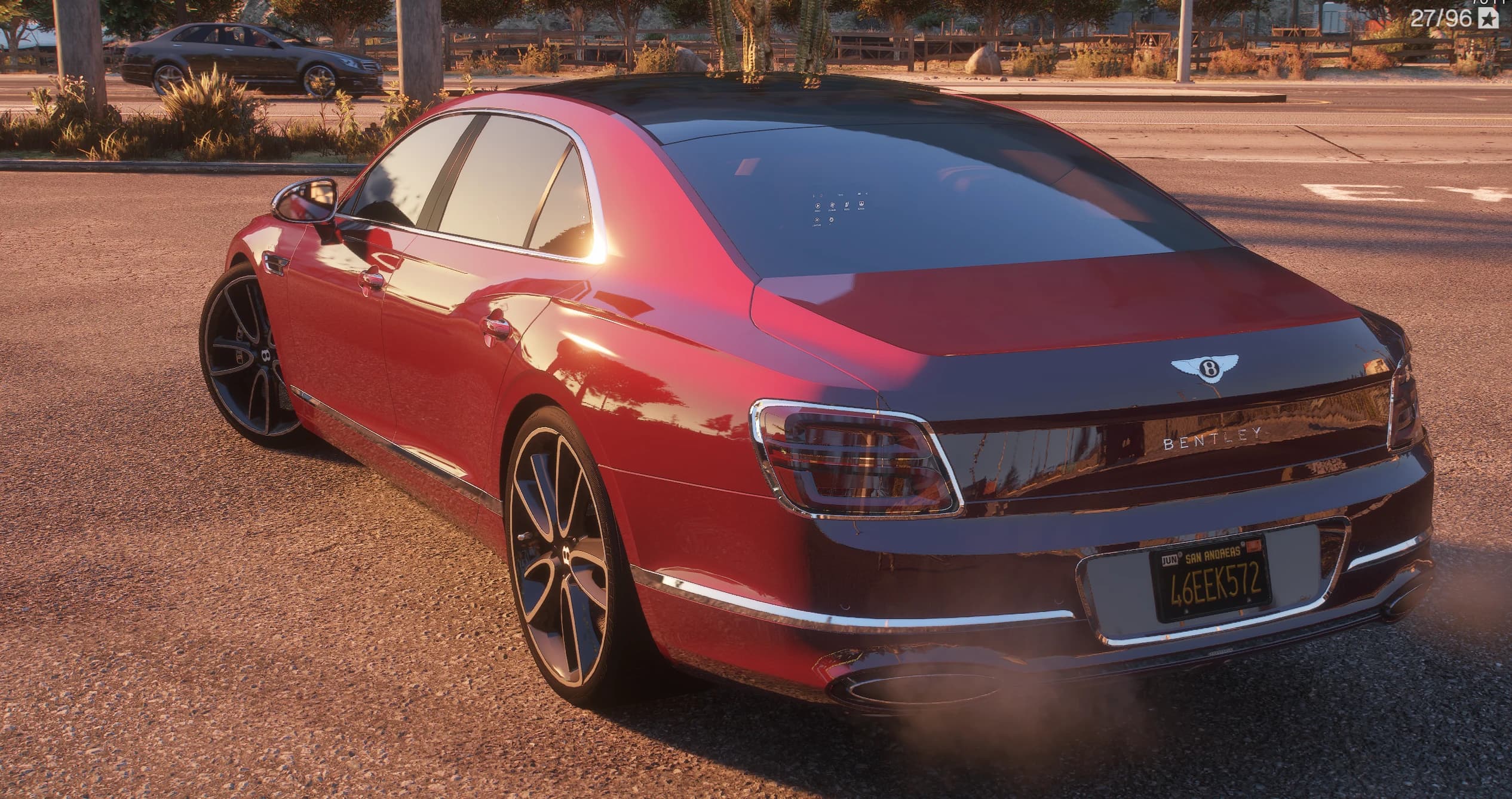 Rear three-quarter of the Flying Spur at sunset with BENTLEY lettering across the tail, the winged B badge on the trunk lid, wraparound tail lights and a yellow San Andreas plate reading 46EEK572