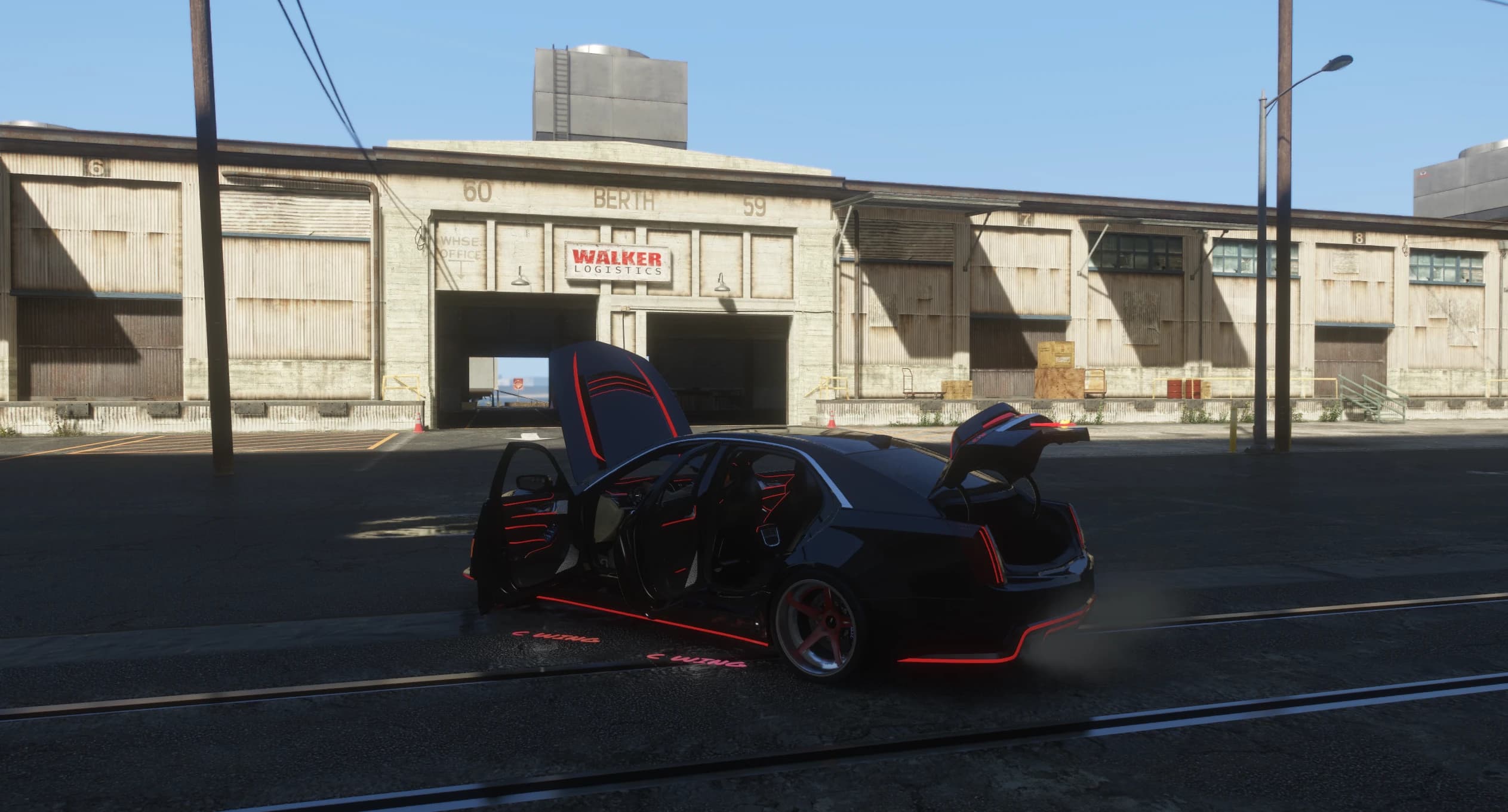The saloon in front of a dockside warehouse with doors, bonnet and boot open and C WING projections beamed onto the road