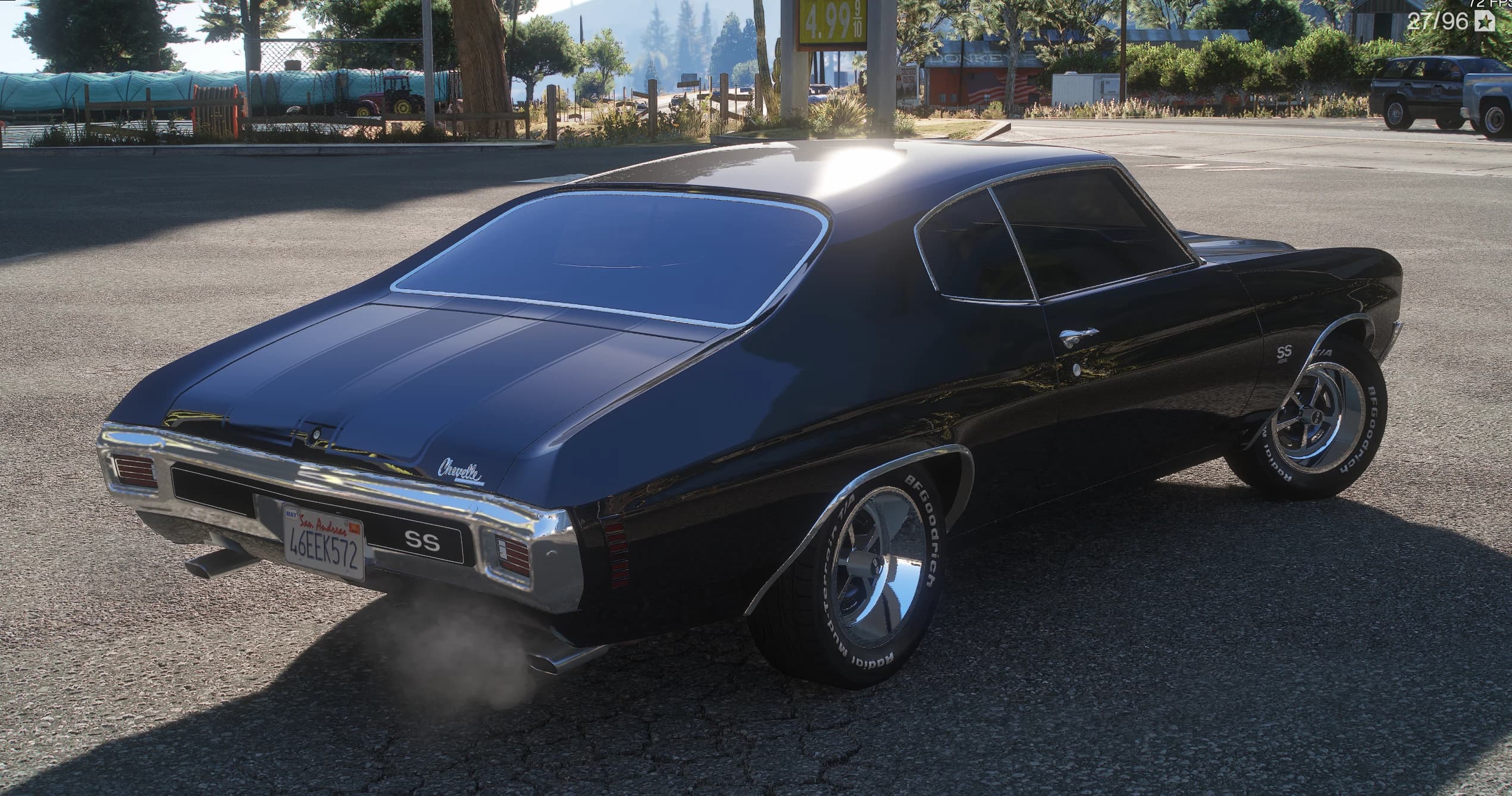Rear three-quarter of the black Chevelle at a petrol station, showing the Chevelle script on the boot lid, the SS badge between the tail lights and smoke from the dual exhaust