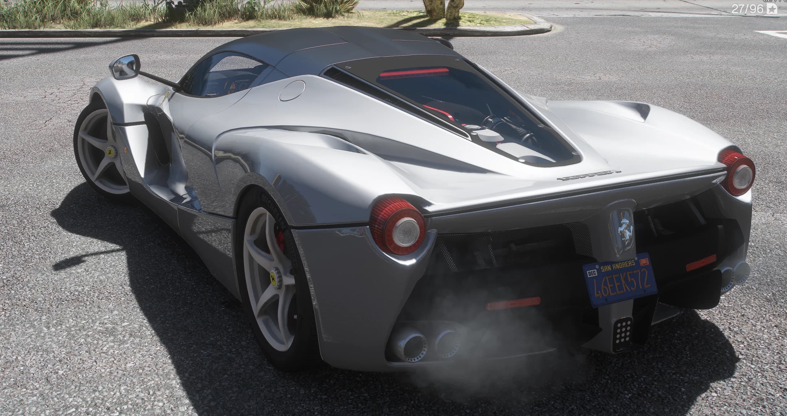Rear three-quarter of the silver LaFerrari showing the V12 under the glass engine cover, the round tail lights, the prancing horse badge and smoke rising from the twin exhausts