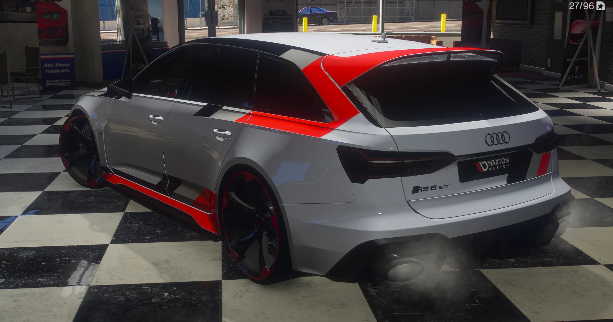 Rear three-quarter of the RS6 GT in the showroom: red panel over the C-pillar and roof spoiler, RS 6 GT badge and four rings on the tailgate, a MAXTON DESIGN plate in the plate recess and oval exhausts trailing smoke
