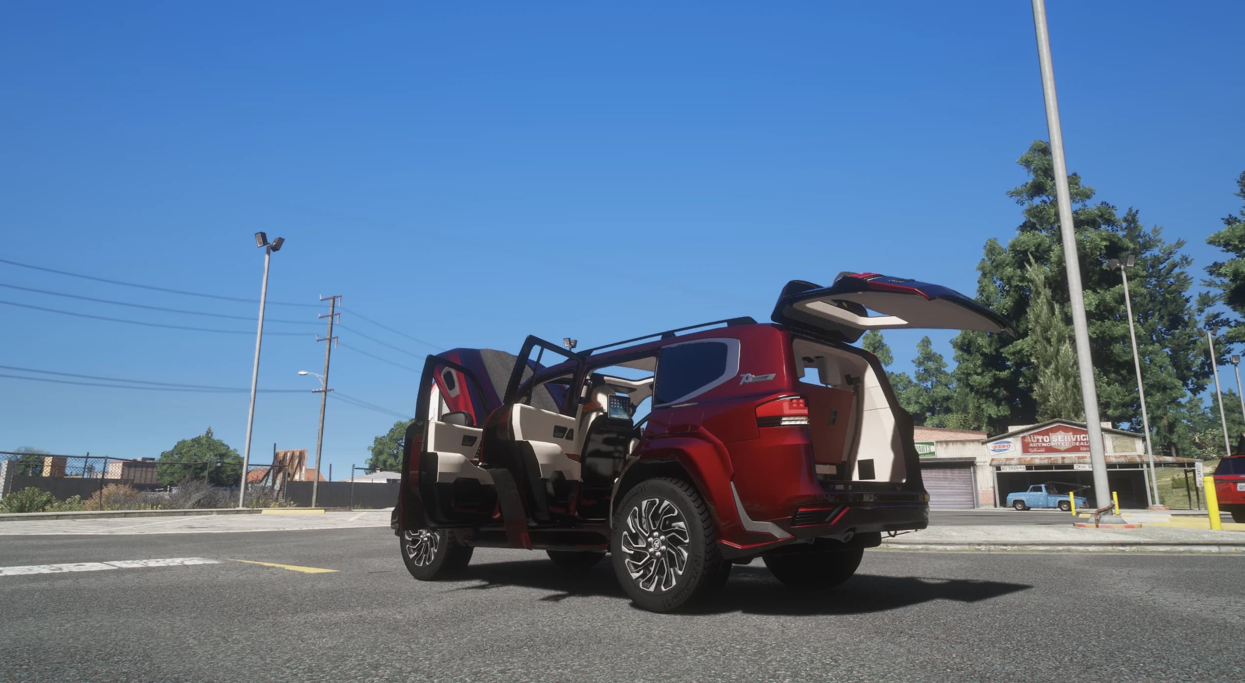Low rear shot with all four doors and the raised tailgate open, showing the cream leather cabin and the roof rails against a blue sky