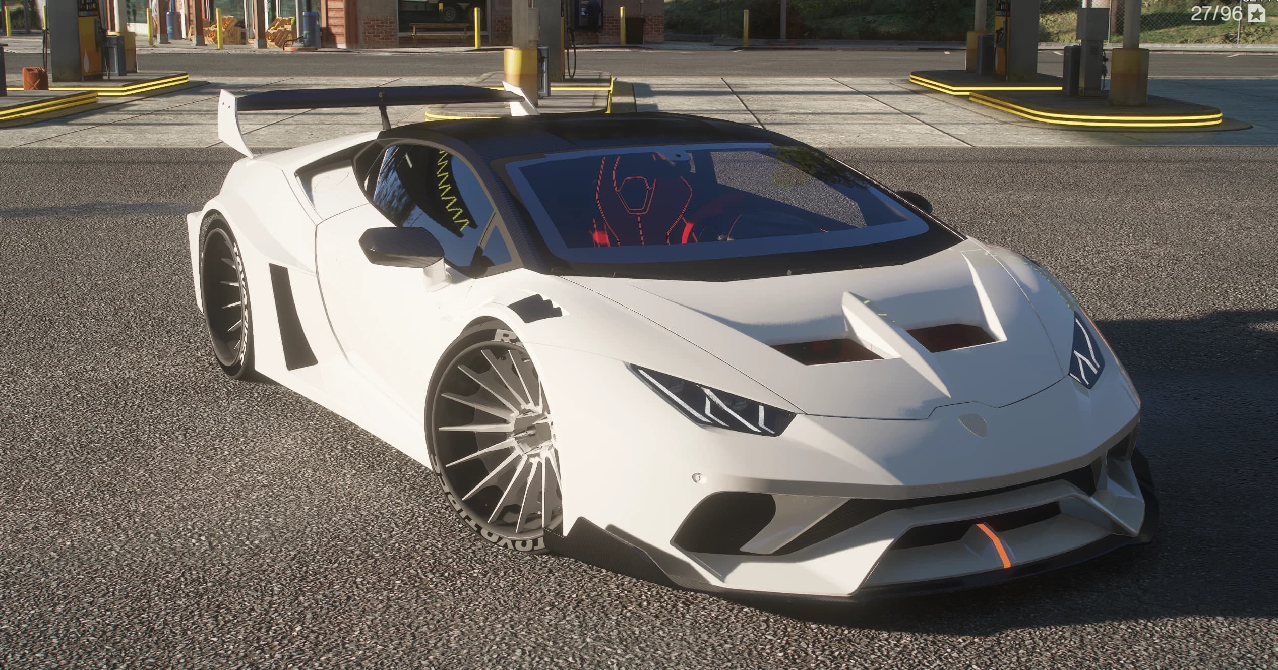 The Huracan on a Los Santos petrol station forecourt in daylight, front three-quarter view showing the carbon roof, the red bucket seats through the windscreen and the carbon front lip