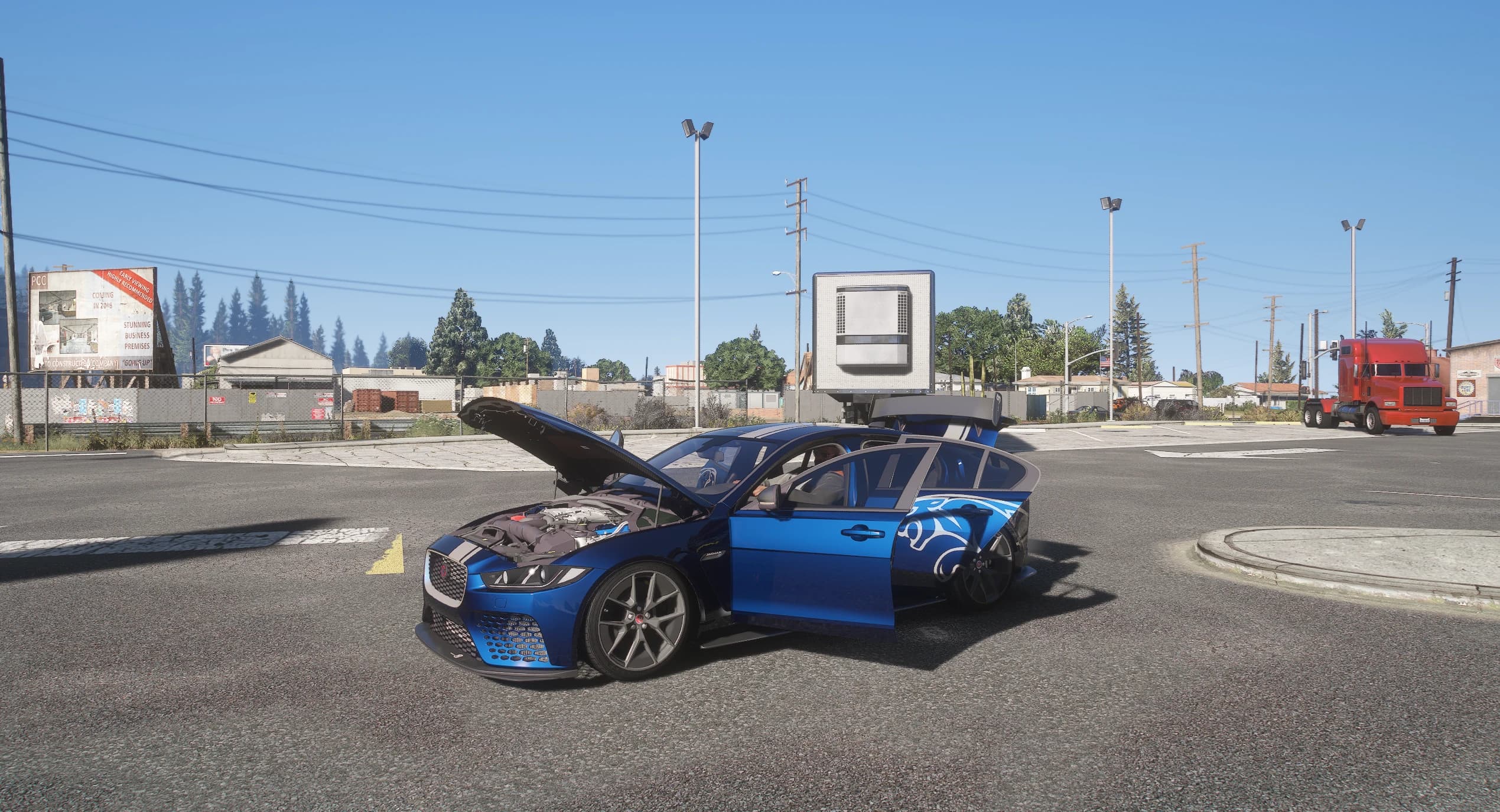The Project 8 stopped at a wide junction with the hood and both left-hand doors open, showing the engine bay and the cabin, with a red truck and industrial buildings behind it