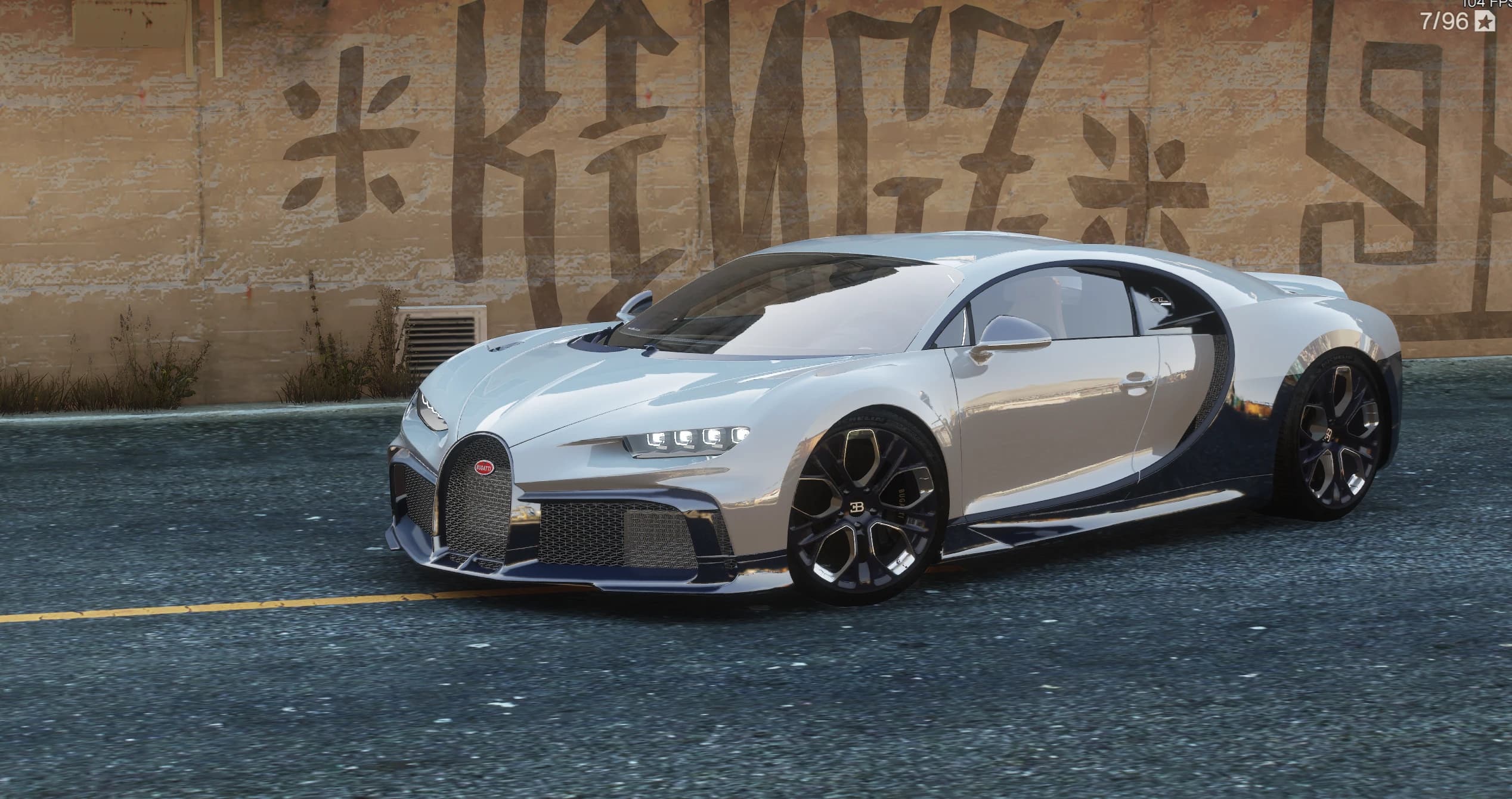 Front three-quarter of the Chiron Profilee from the driver's side, parked on asphalt in front of a graffiti-covered concrete wall at the docks