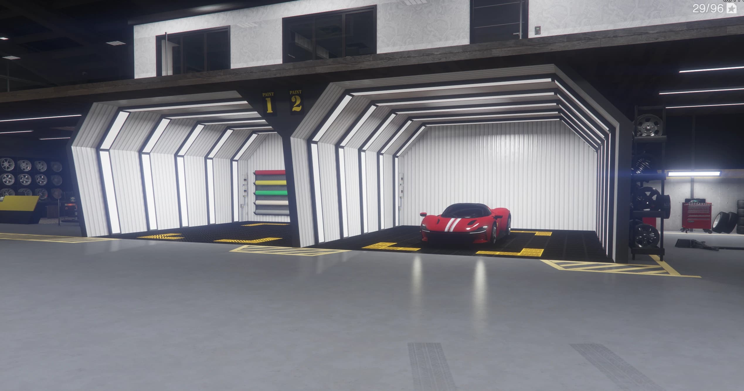 The two numbered paint booths with a red supercar parked inside booth two and wheel racks on the sides