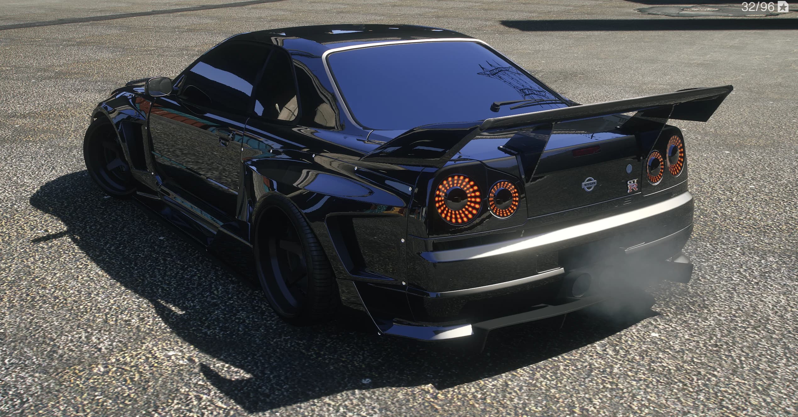 Rear three quarter of the black R34 GT-R with the big rear wing and round LED taillights lit up